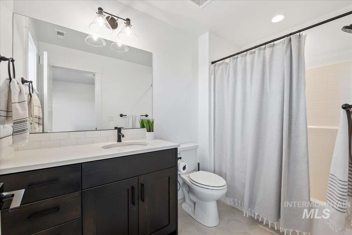 Bathroom featuring light tile patterned flooring, shower / bath combo with shower curtain, and vanity