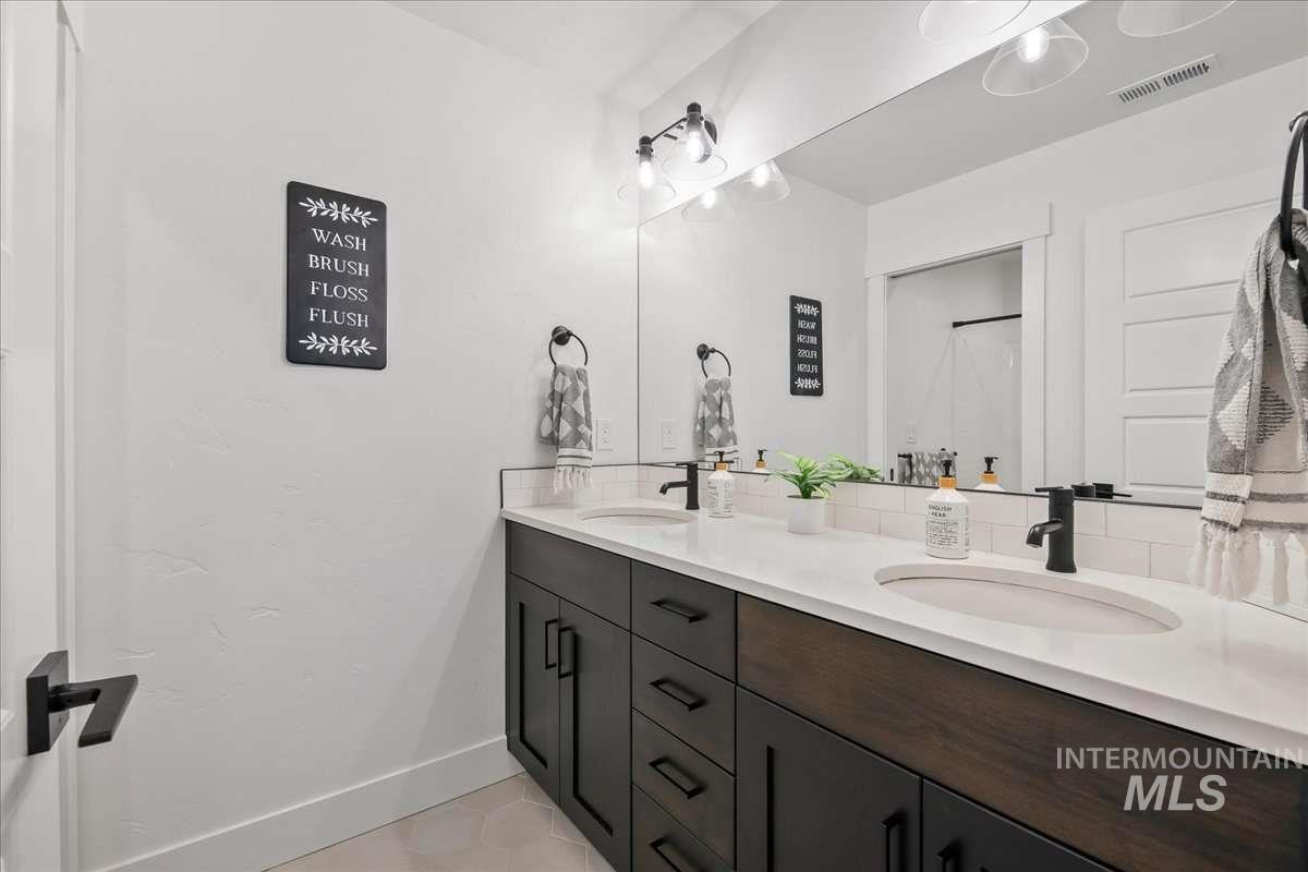 Full bathroom with double vanity, light tile patterned floors, and a shower with shower curtain