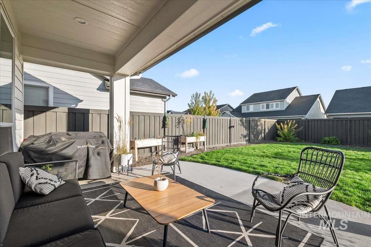 Fenced backyard featuring a patio, grilling area, and a residential view