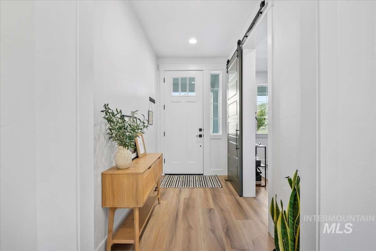 Doorway to outside with wood finished floors, a barn door, and recessed lighting