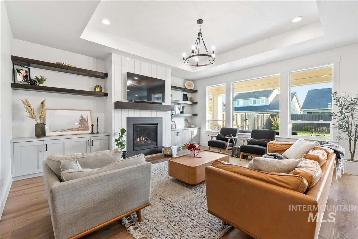 Living area featuring a tray ceiling, light wood-type flooring, a fireplace, and recessed lighting