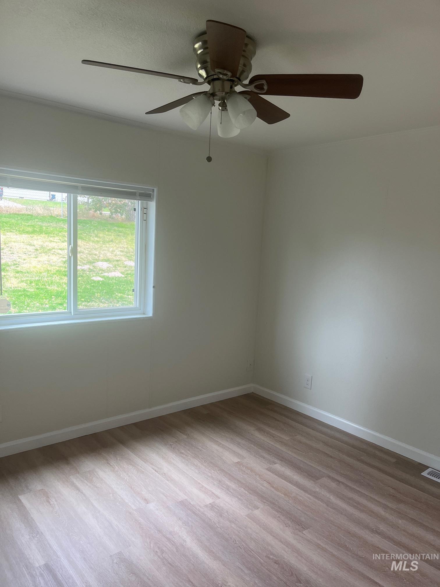 Unfurnished room featuring light wood-style flooring and ceiling fan
