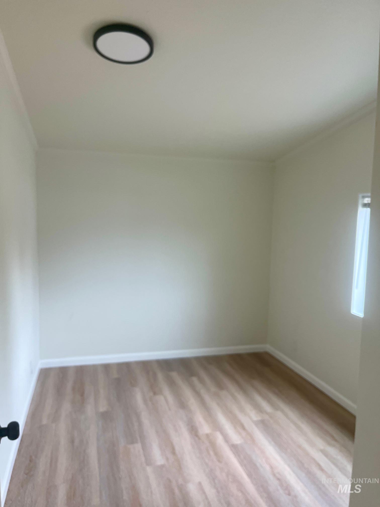 Empty room with light wood-style flooring and baseboards