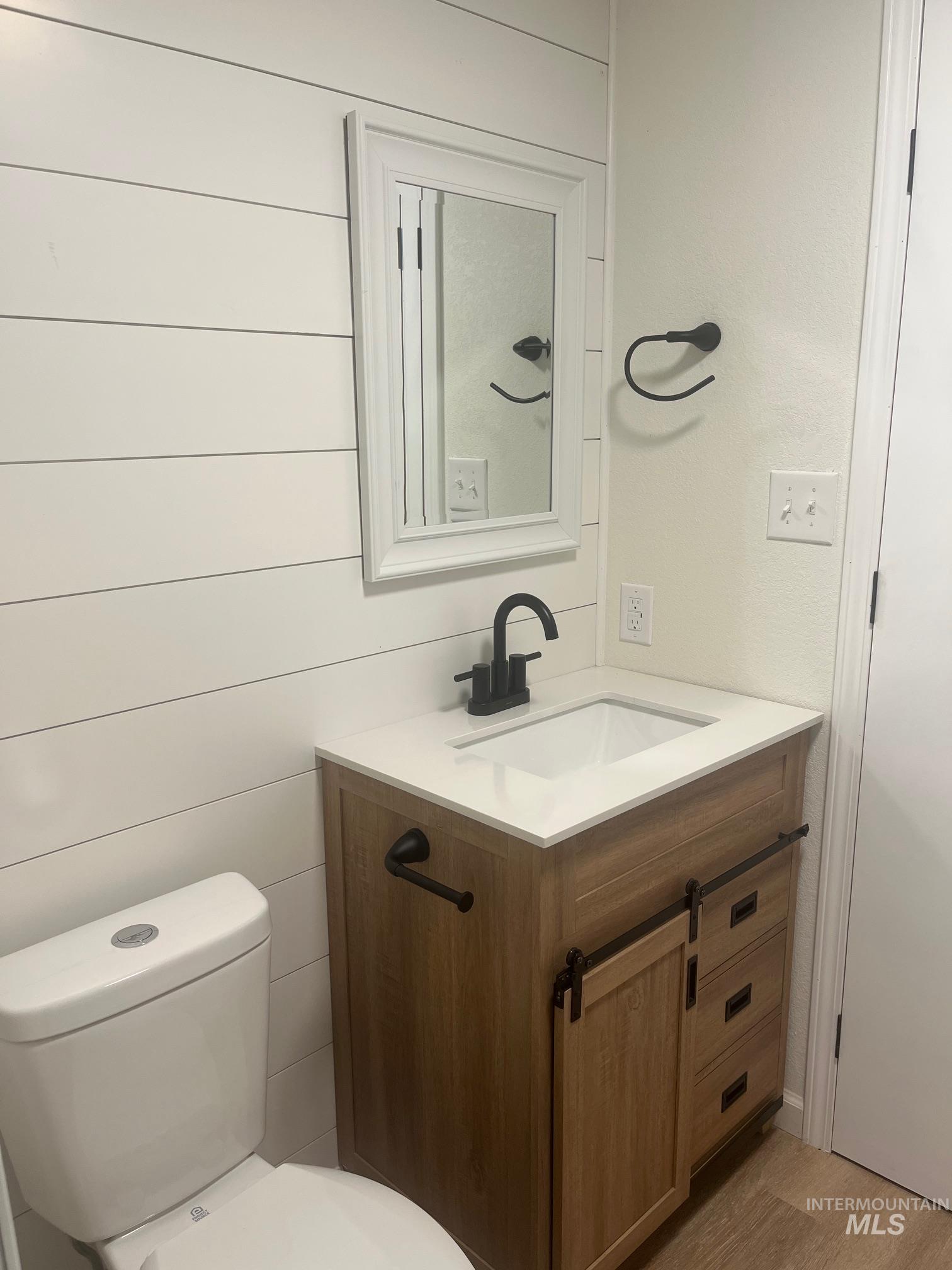 Bathroom with vanity, light wood finished floors, and wood walls