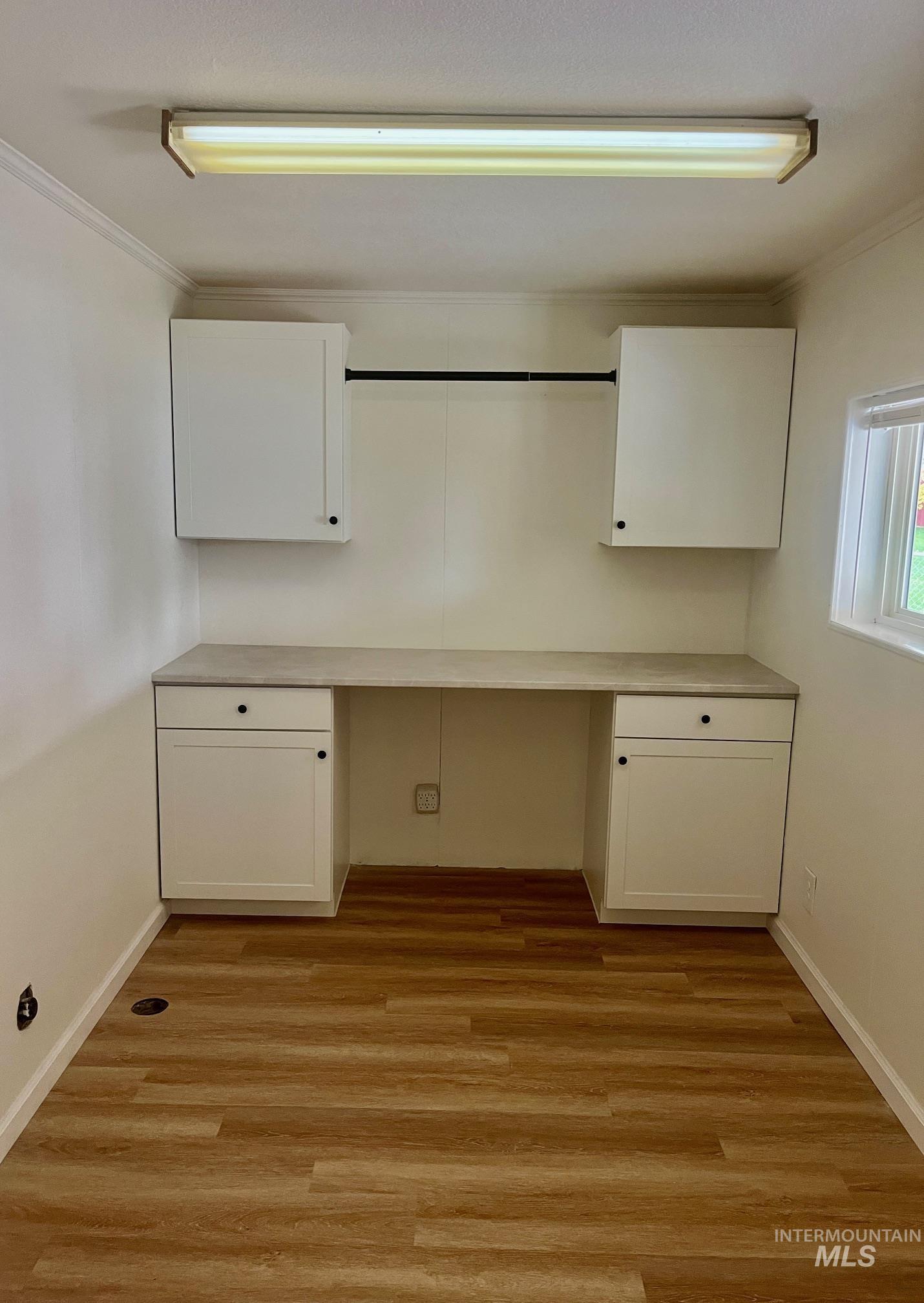 Laundry area with an office area, ornamental molding, and light wood-type flooring