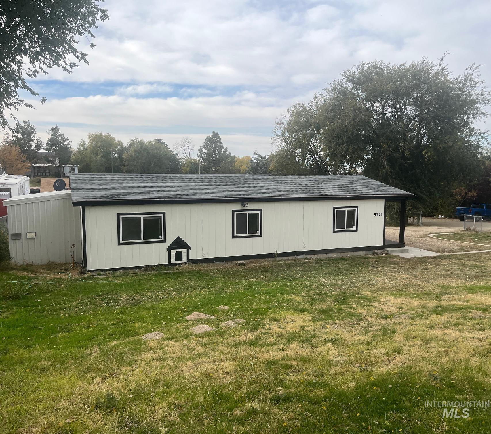 View of side of property featuring a yard and roof with shingles