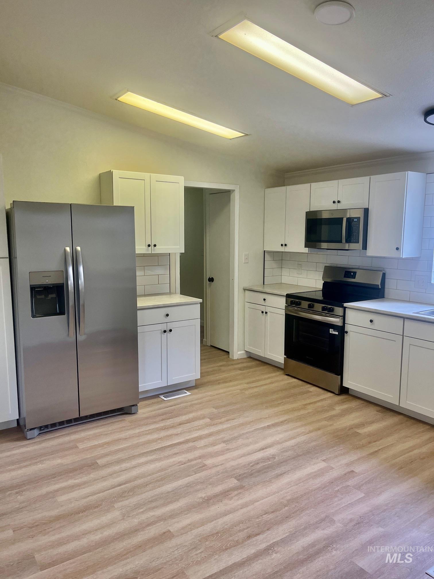 Kitchen featuring white cabinetry, stainless steel appliances, and tasteful backsplash