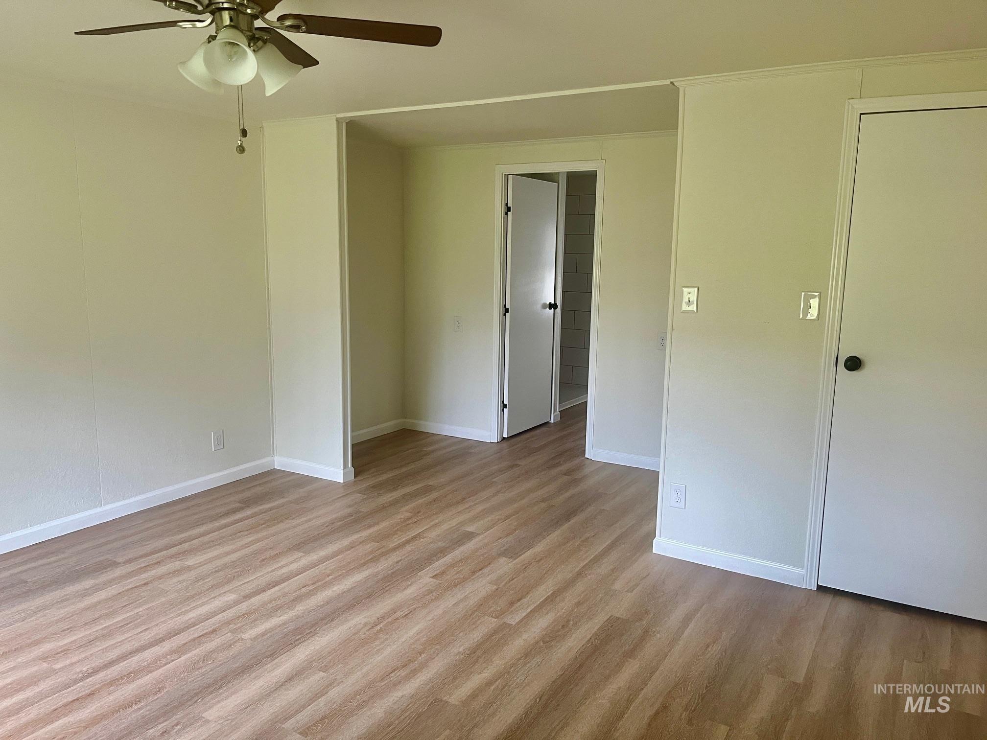 Empty room with light wood finished floors and ceiling fan