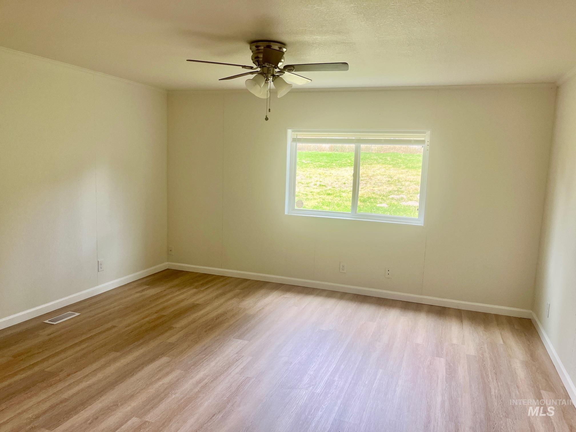 Empty room featuring light wood-type flooring and ceiling fan