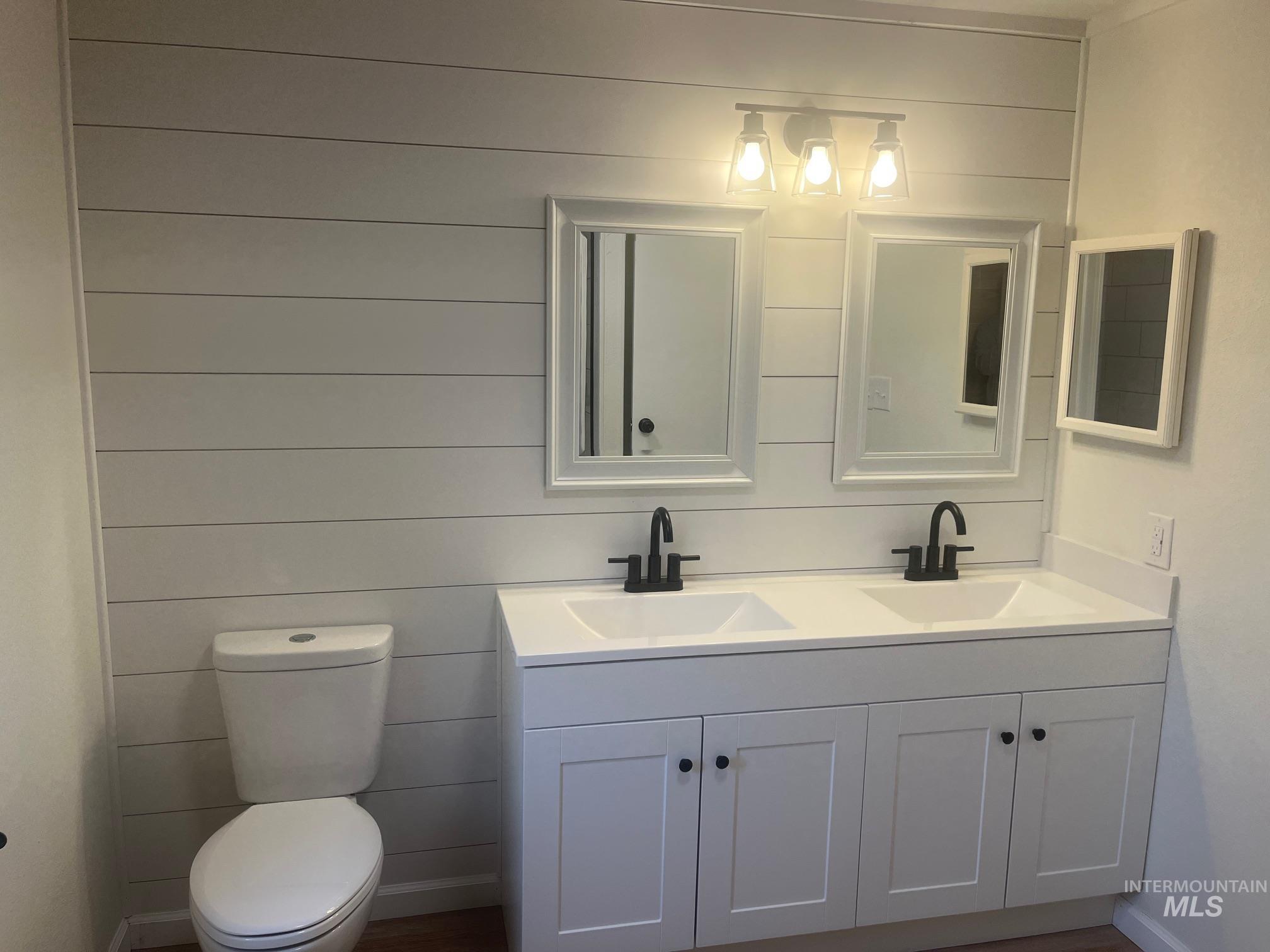 Full bath with double vanity and wooden walls
