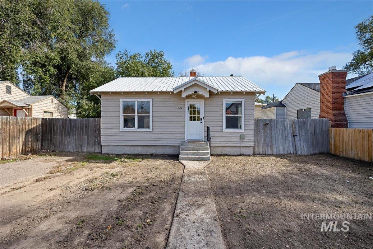 Bungalow-style home featuring a metal roof, a fenced backyard, and entry steps