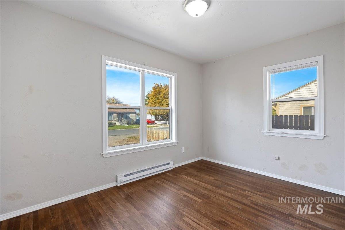 Empty room featuring a baseboard radiator and dark wood-style floors