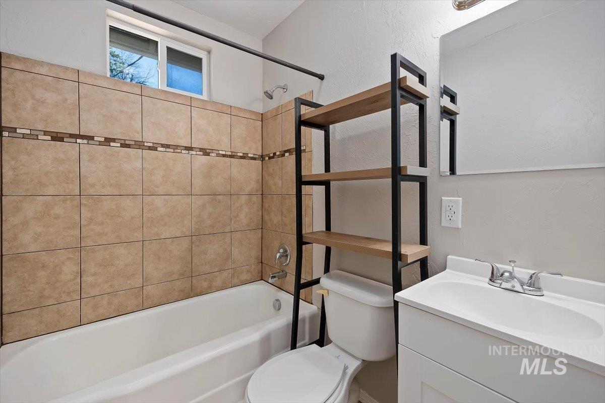 Bathroom featuring shower / bathtub combination, vanity, and a textured wall