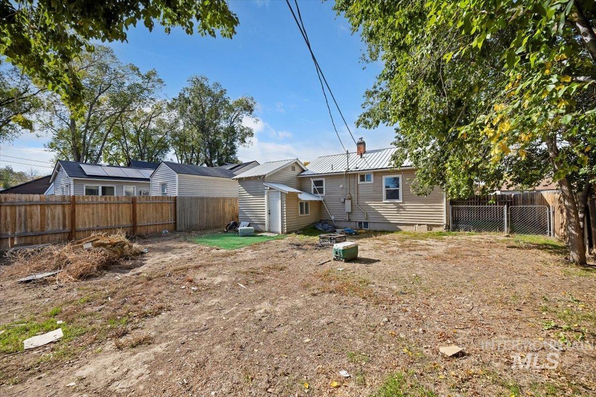 Back of property with a metal roof, a fenced backyard, a chimney, crawl space, and a storage unit