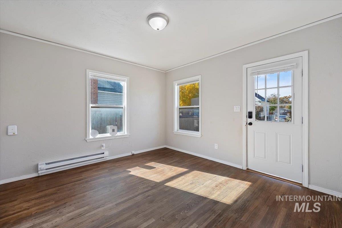 Foyer with a baseboard radiator, dark wood-type flooring, and ornamental molding