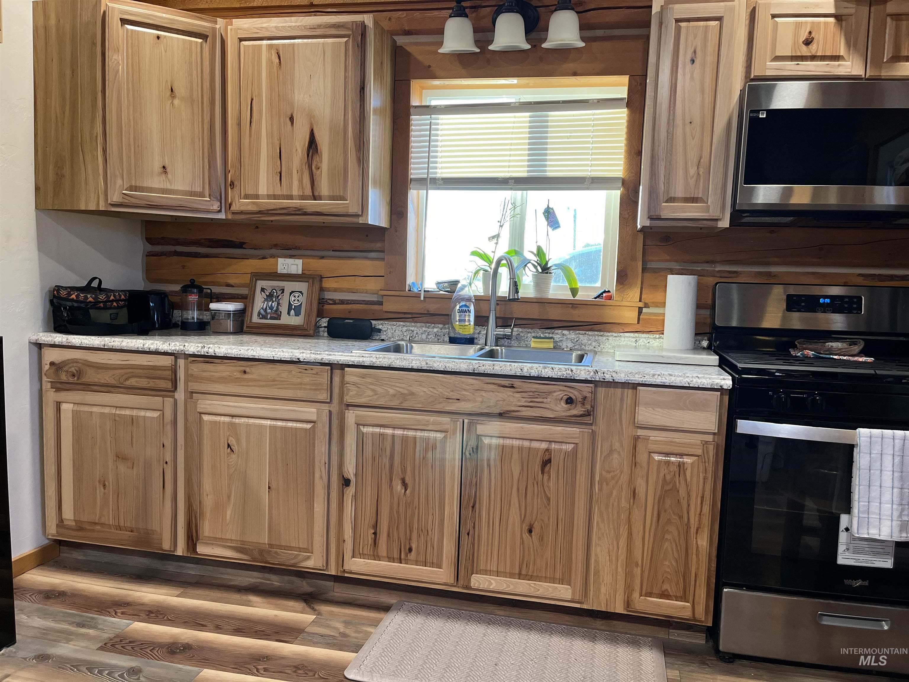 Kitchen with appliances with stainless steel finishes, dark wood-style floors, and brown cabinetry