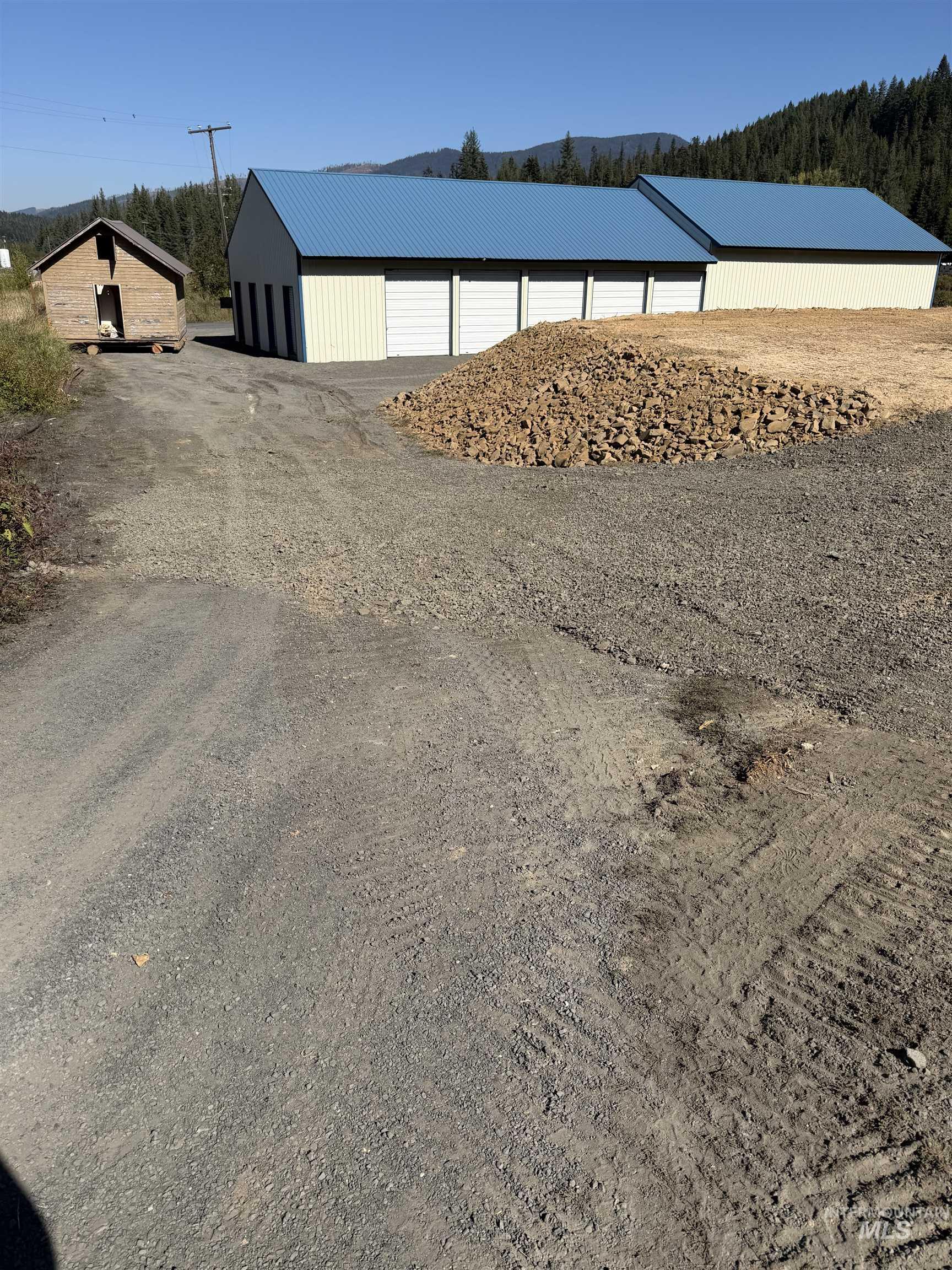 View of dirt / gravel driveway featuring a pole building and a wooded view