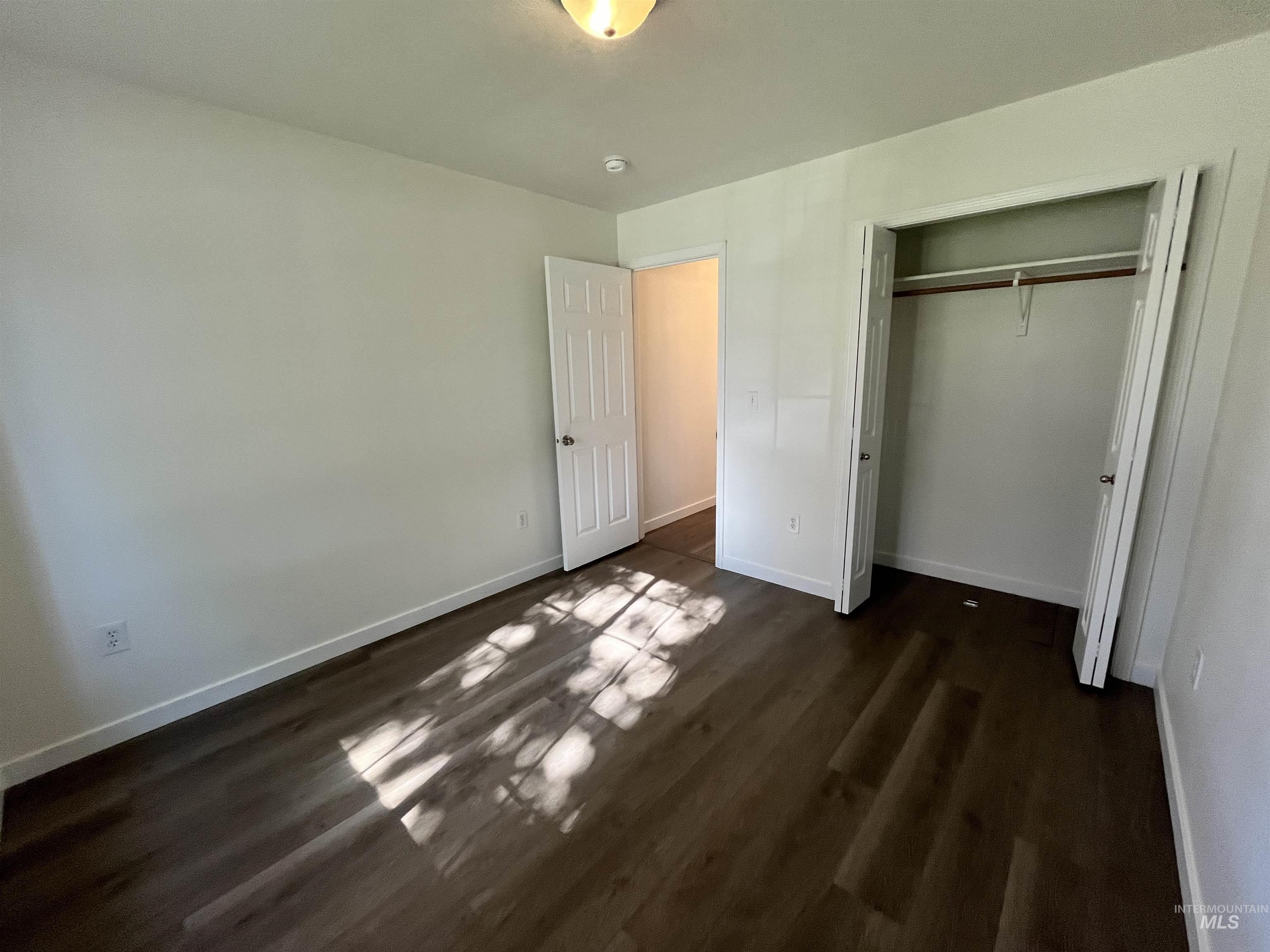 Unfurnished bedroom with dark wood-type flooring and a closet