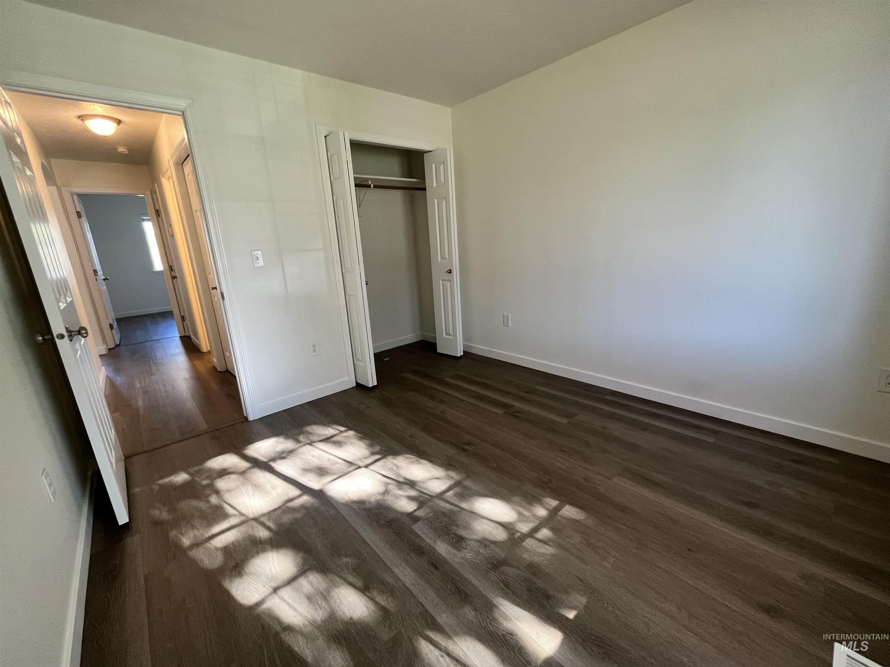 Unfurnished bedroom featuring dark wood-style floors and a closet