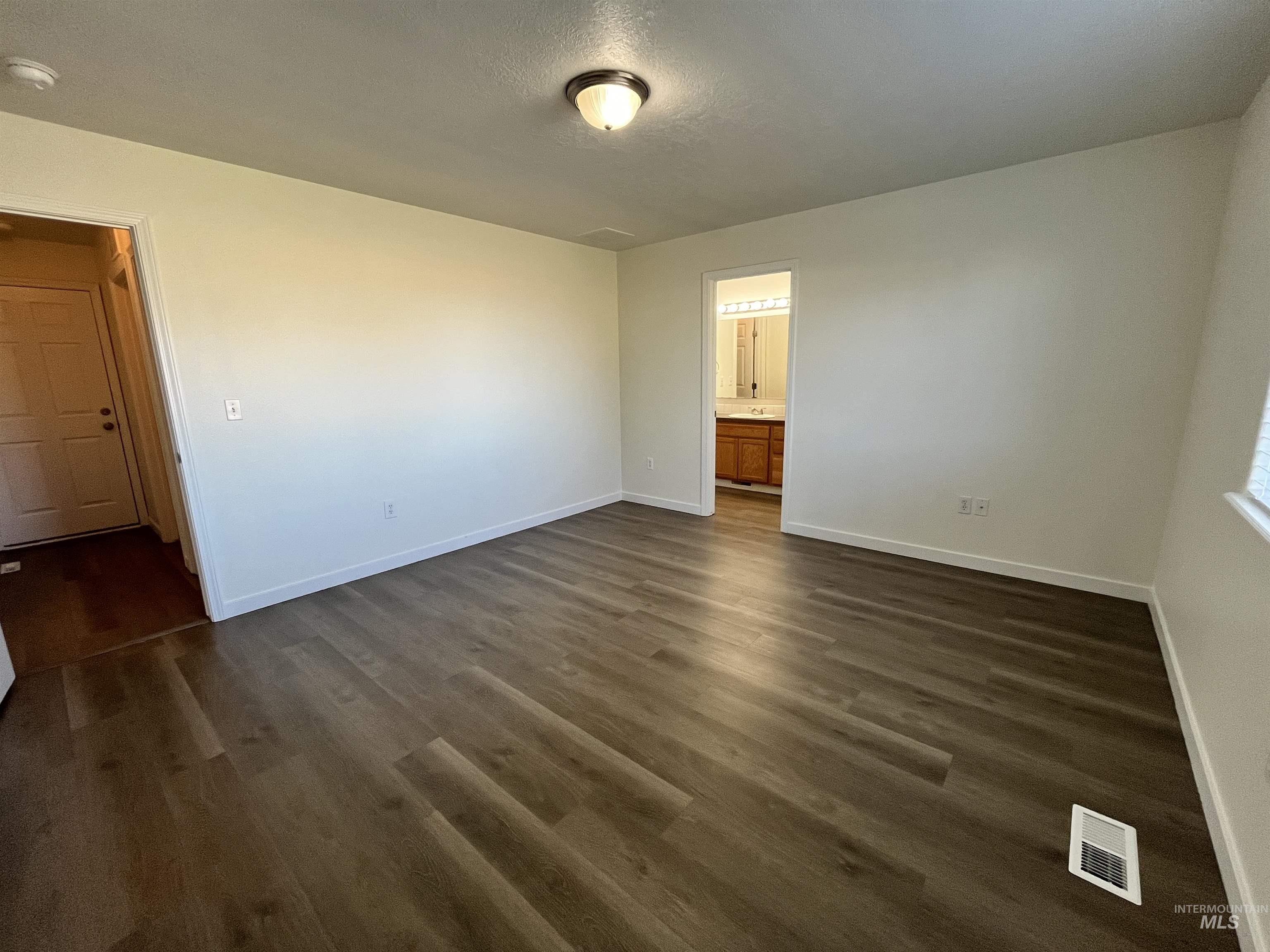 Spare room featuring dark wood finished floors, a textured ceiling, and a smoke detector