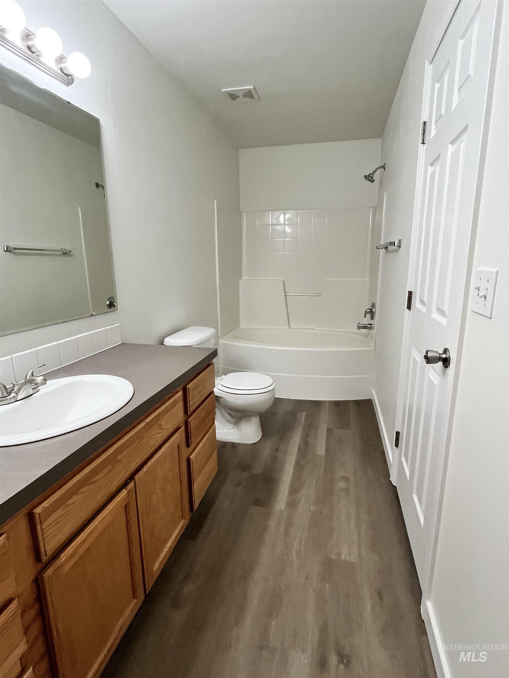 Full bathroom with vanity, shower / bathtub combination, and dark wood finished floors