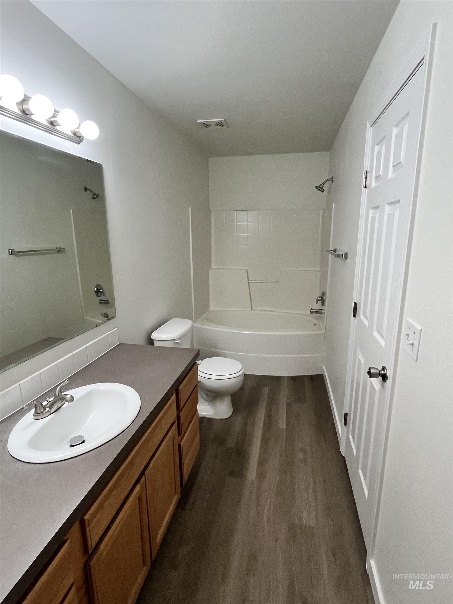 Bathroom with dark wood-style floors, vanity, and shower / tub combination