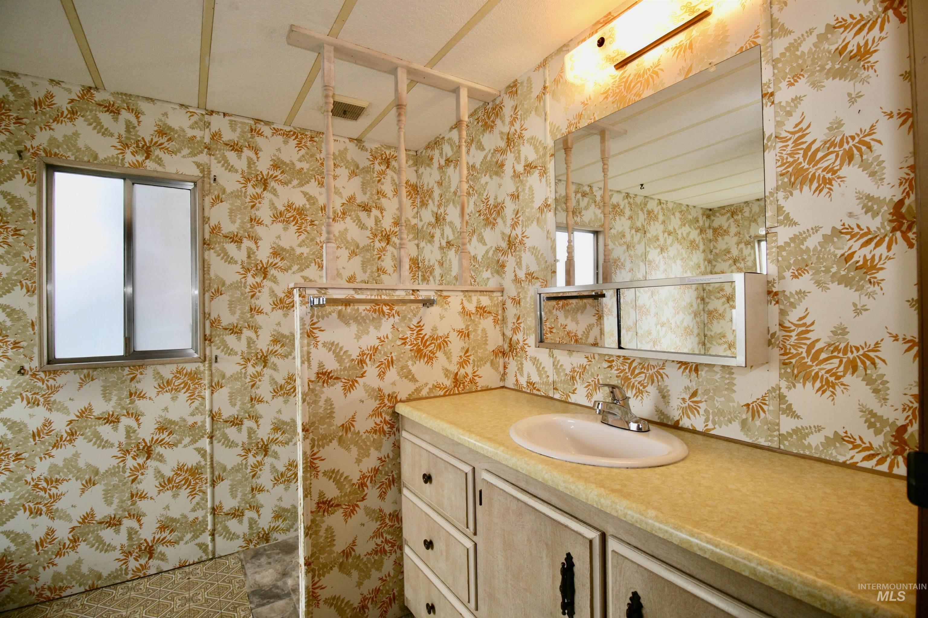 Bathroom featuring wallpapered walls and vanity