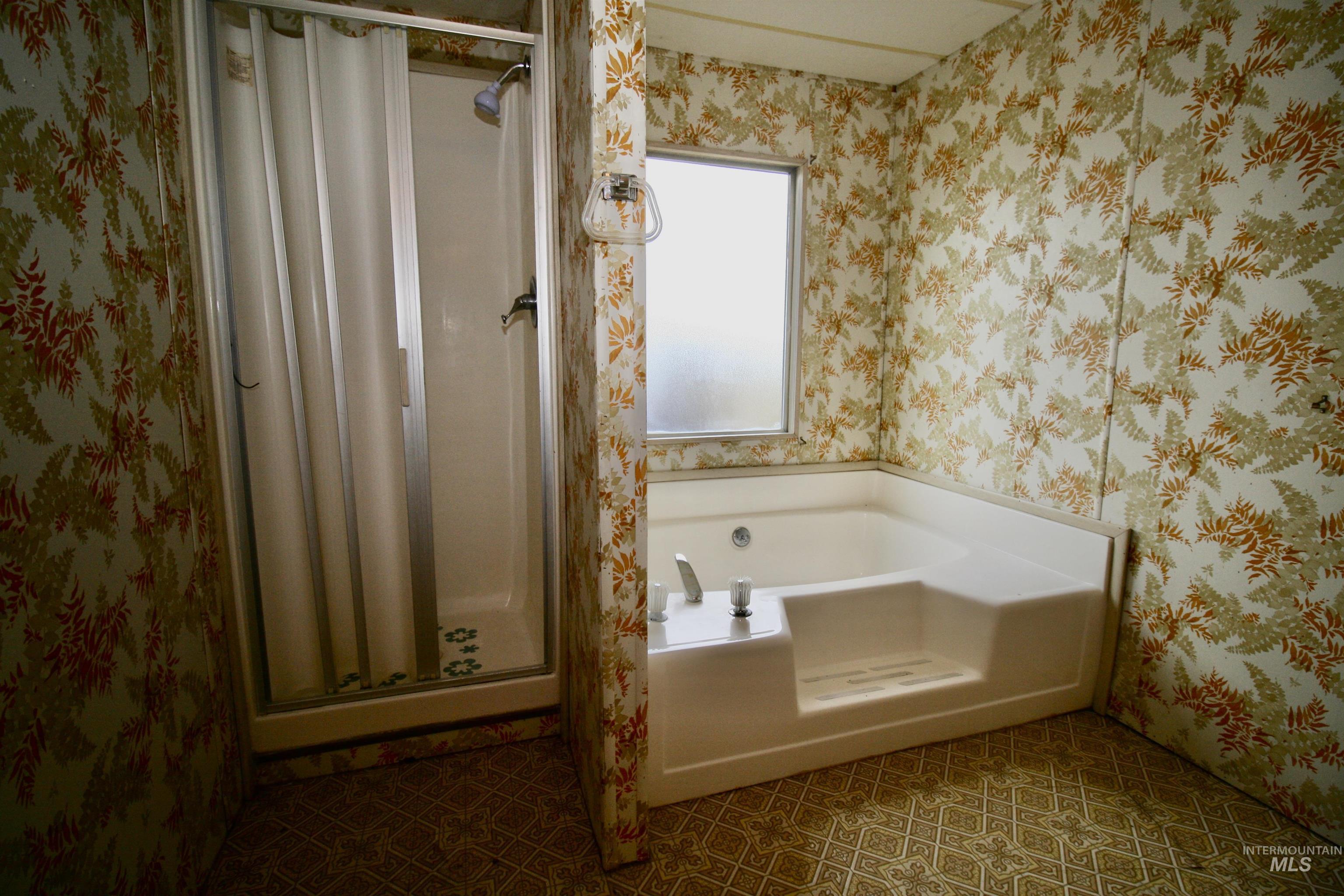 Bathroom featuring wallpapered walls, a bath, a shower stall, and tile patterned flooring