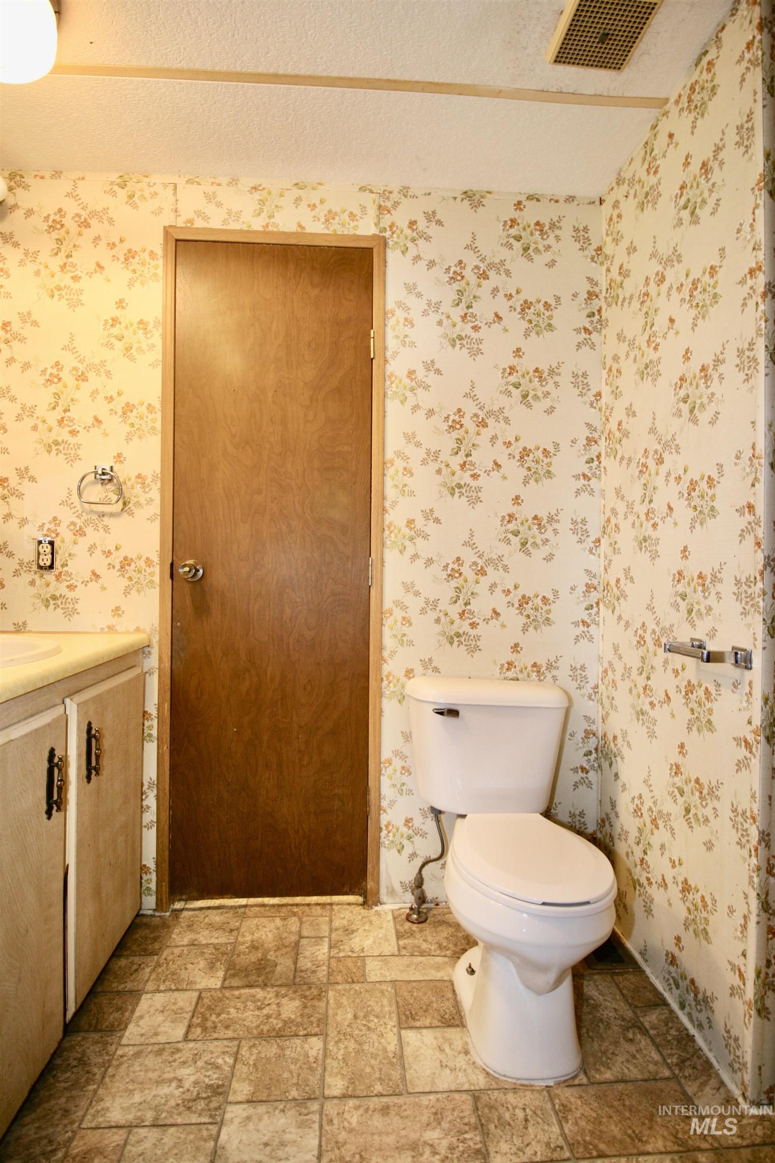 Half bathroom with vanity, a textured ceiling, and light stone finish floors