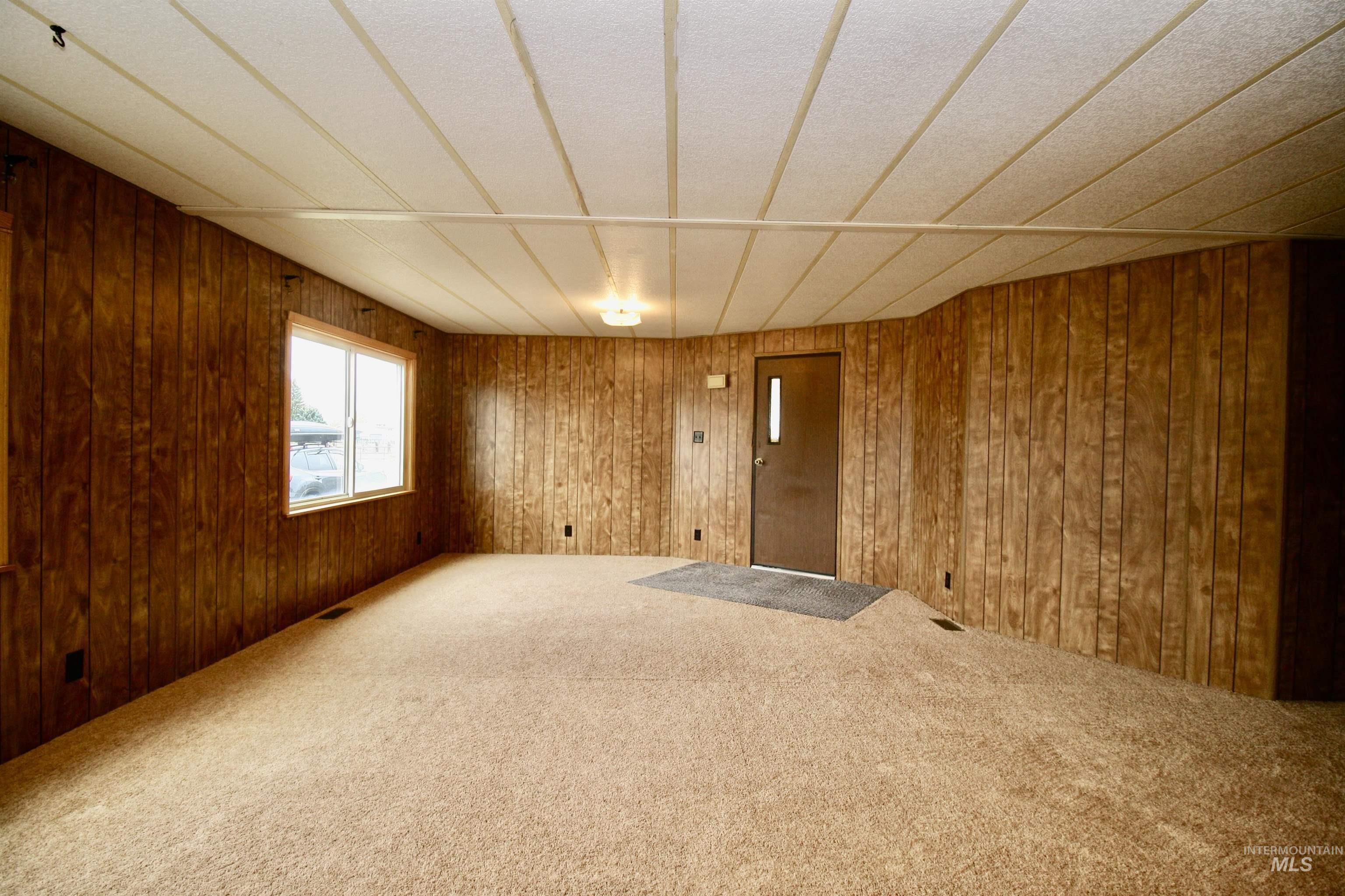 Carpeted empty room featuring wooden walls