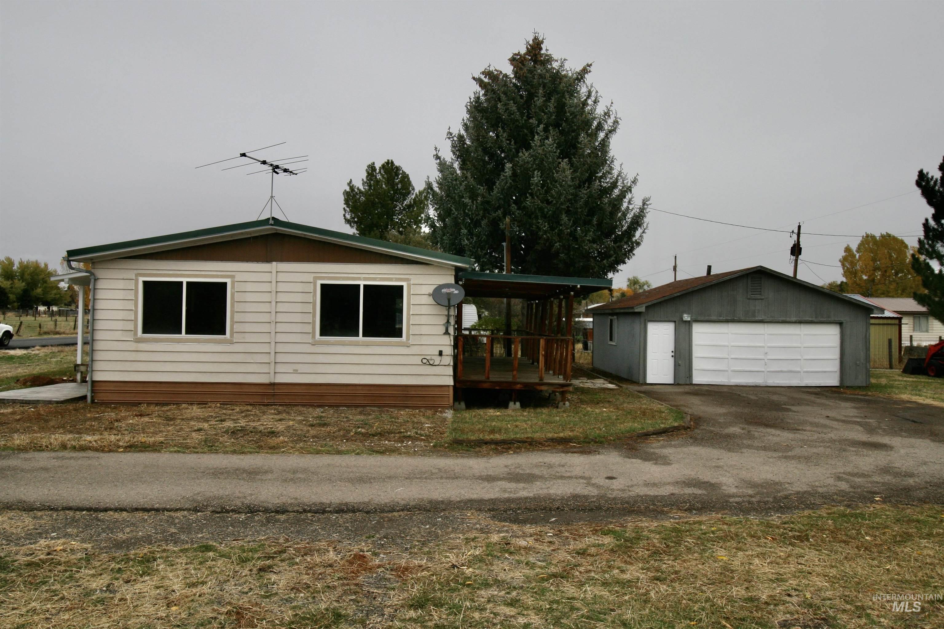 View of front of property featuring an outdoor structure, a detached garage, and a wooden deck