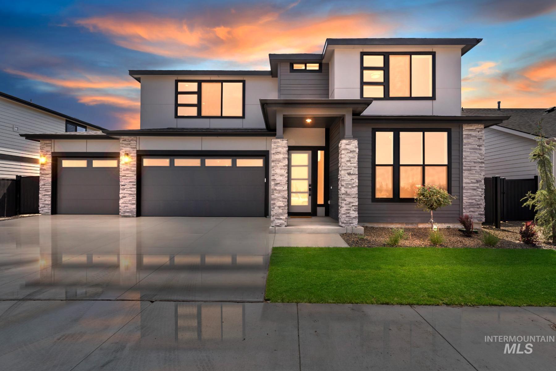 Modern home with stone siding, concrete driveway, stucco siding, and an attached garage