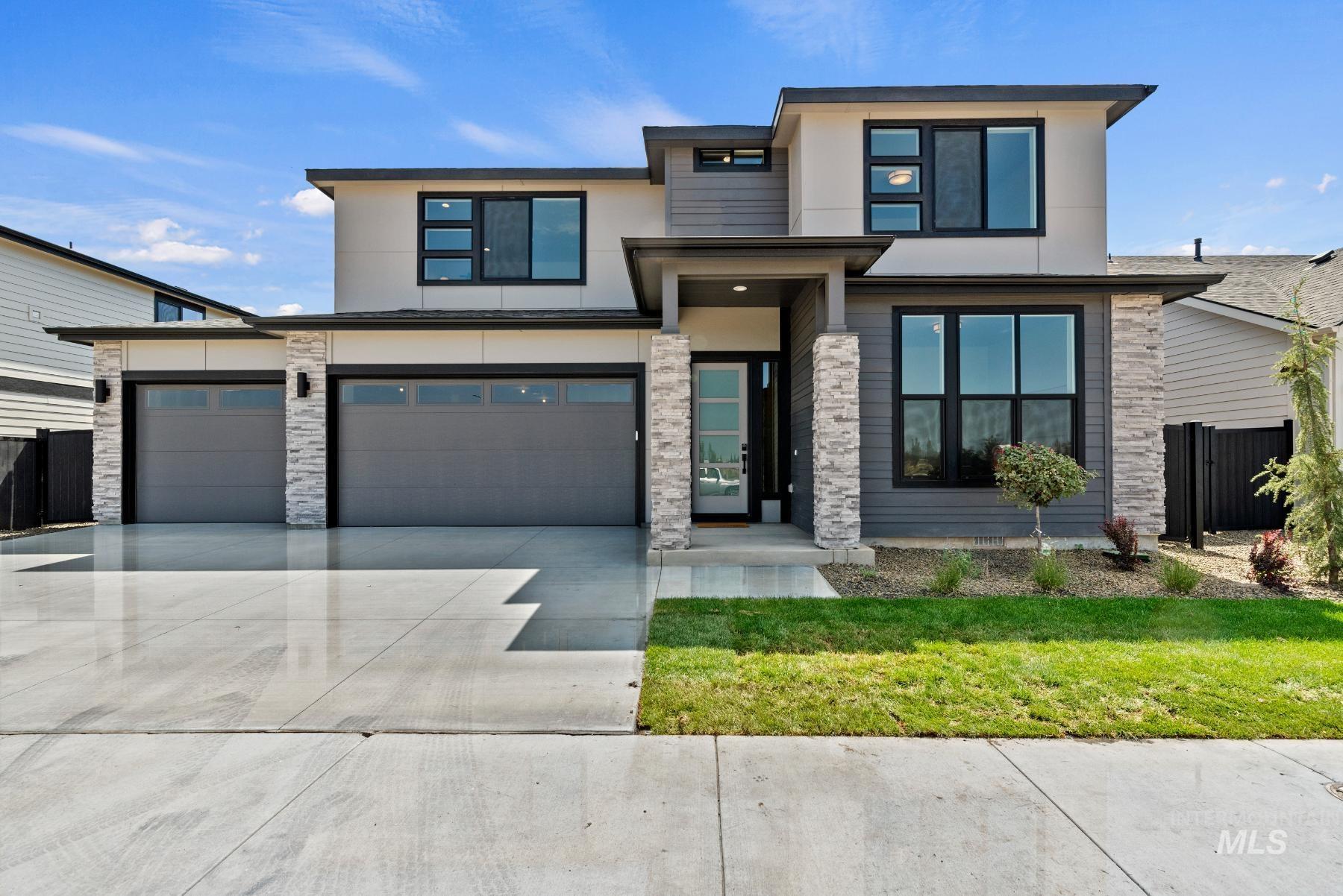 Contemporary house with stucco siding, driveway, an attached garage, and stone siding