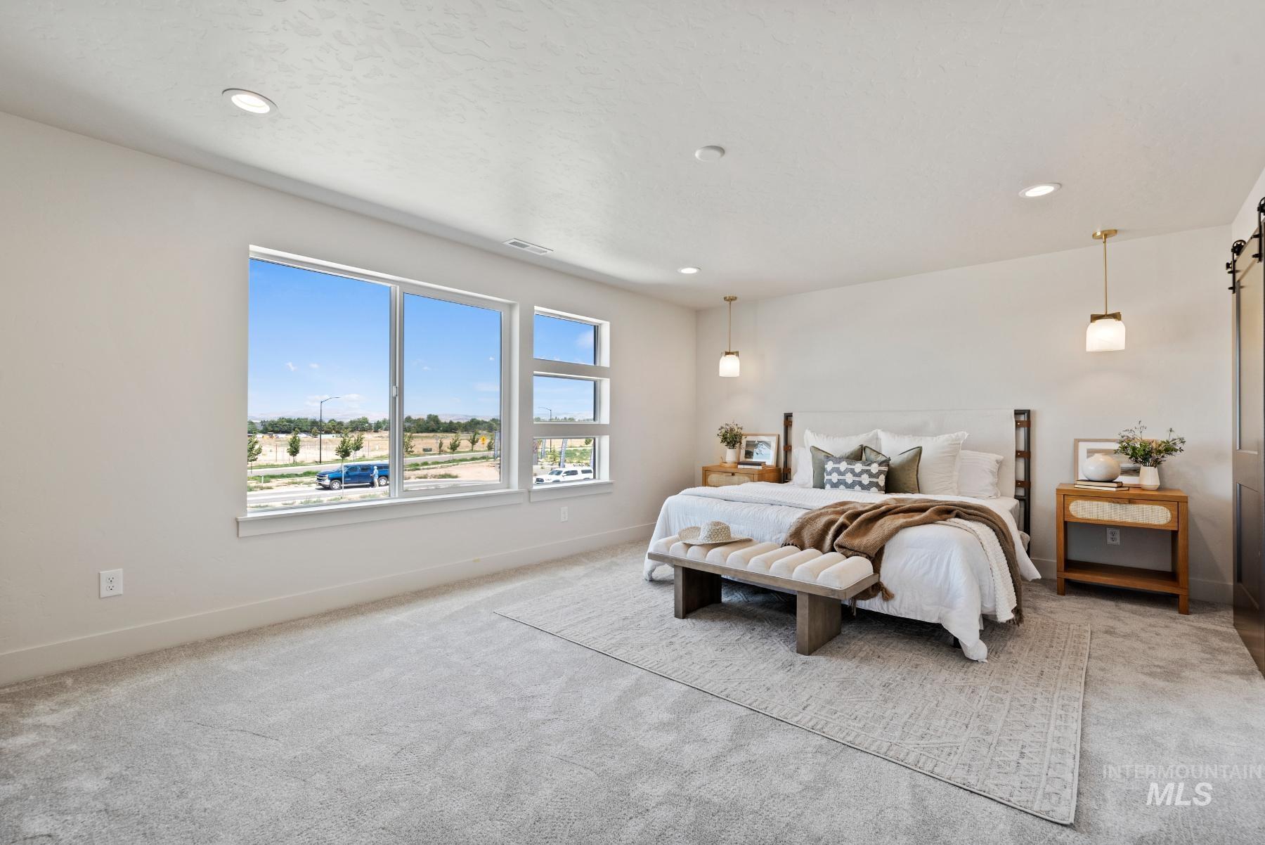 Carpeted bedroom with recessed lighting and a barn door