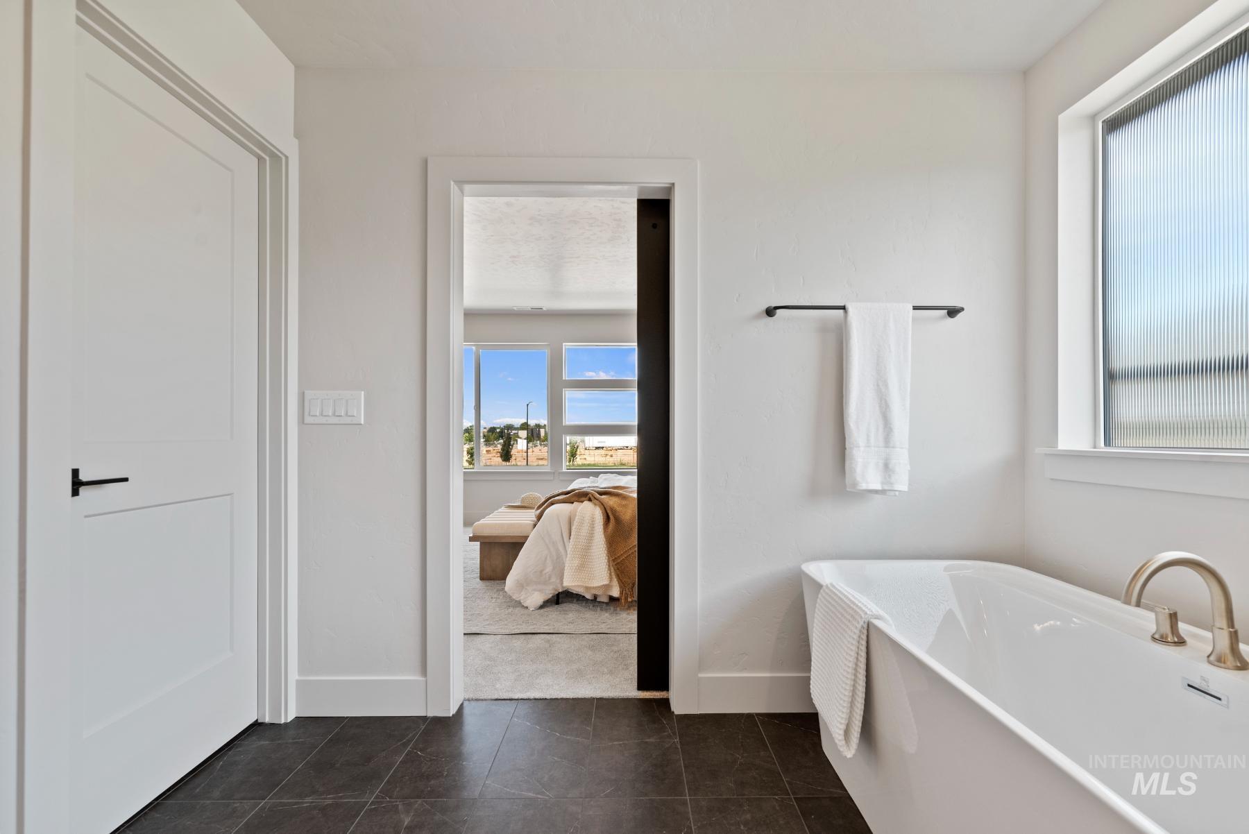 Ensuite bathroom with a soaking tub and dark tile patterned floors