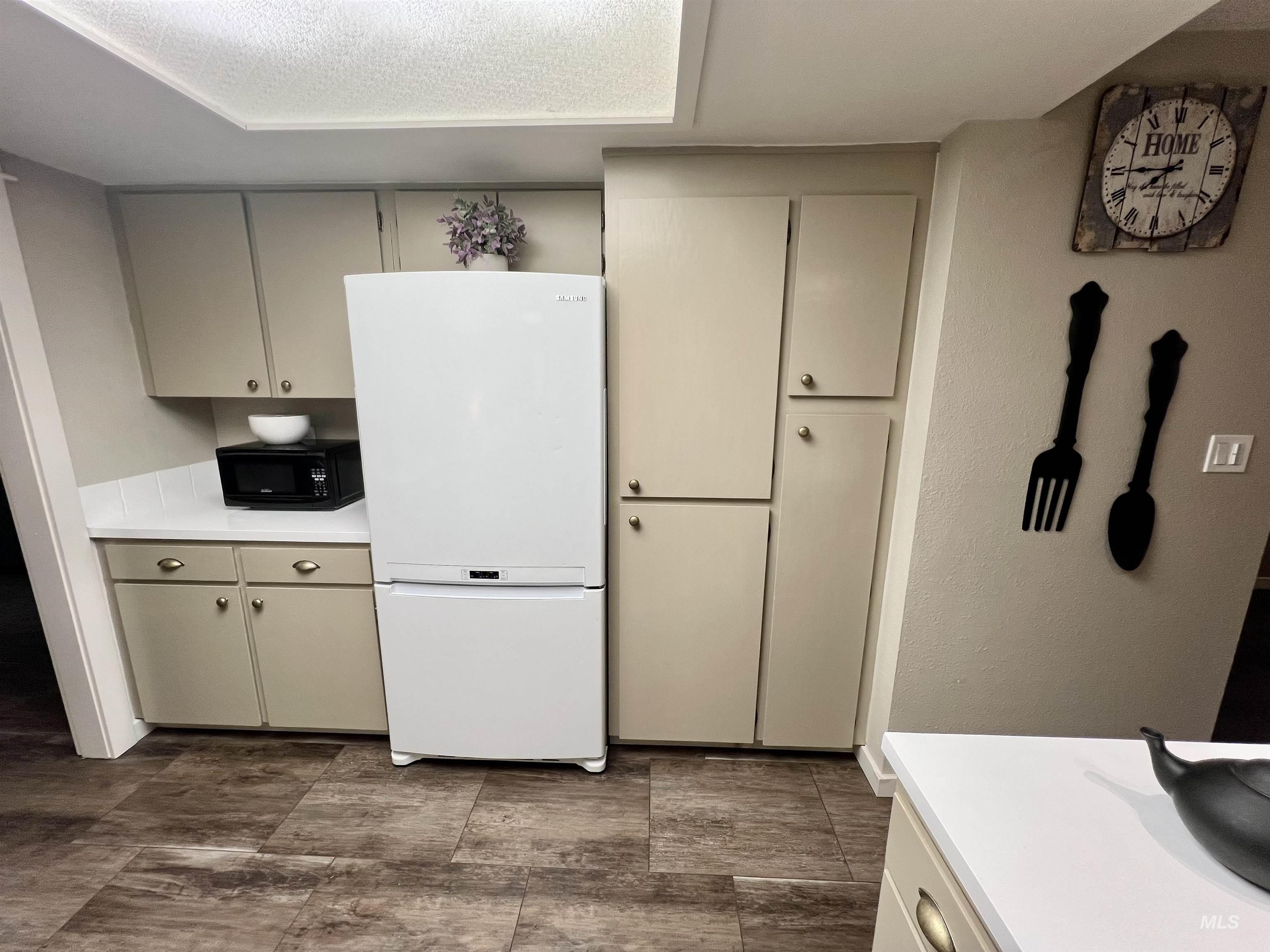 Kitchen featuring light countertops, freestanding refrigerator, black microwave, and gray cabinets