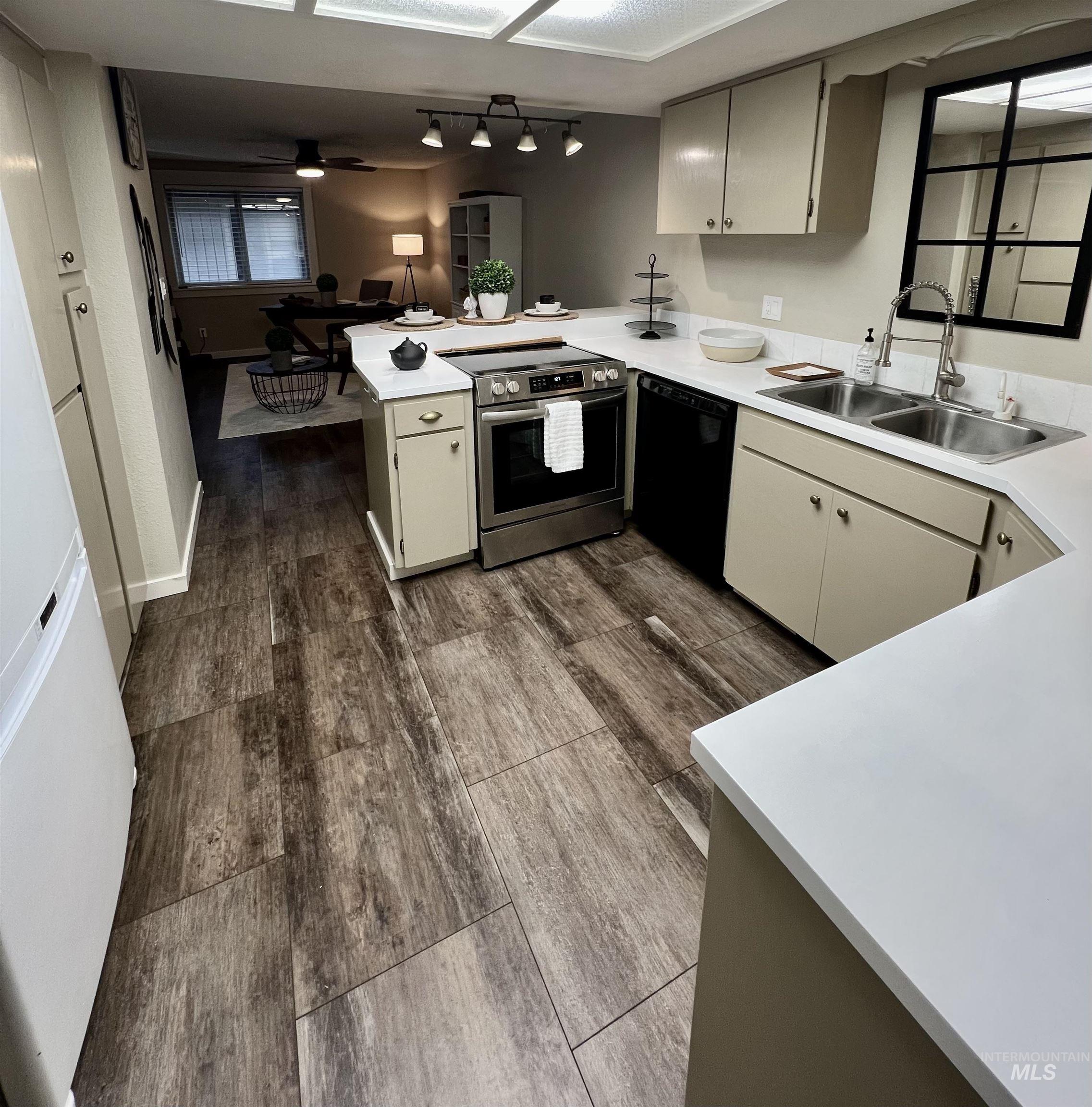 Kitchen with stainless steel range with electric stovetop, light countertops, a peninsula, and dark wood-style floors
