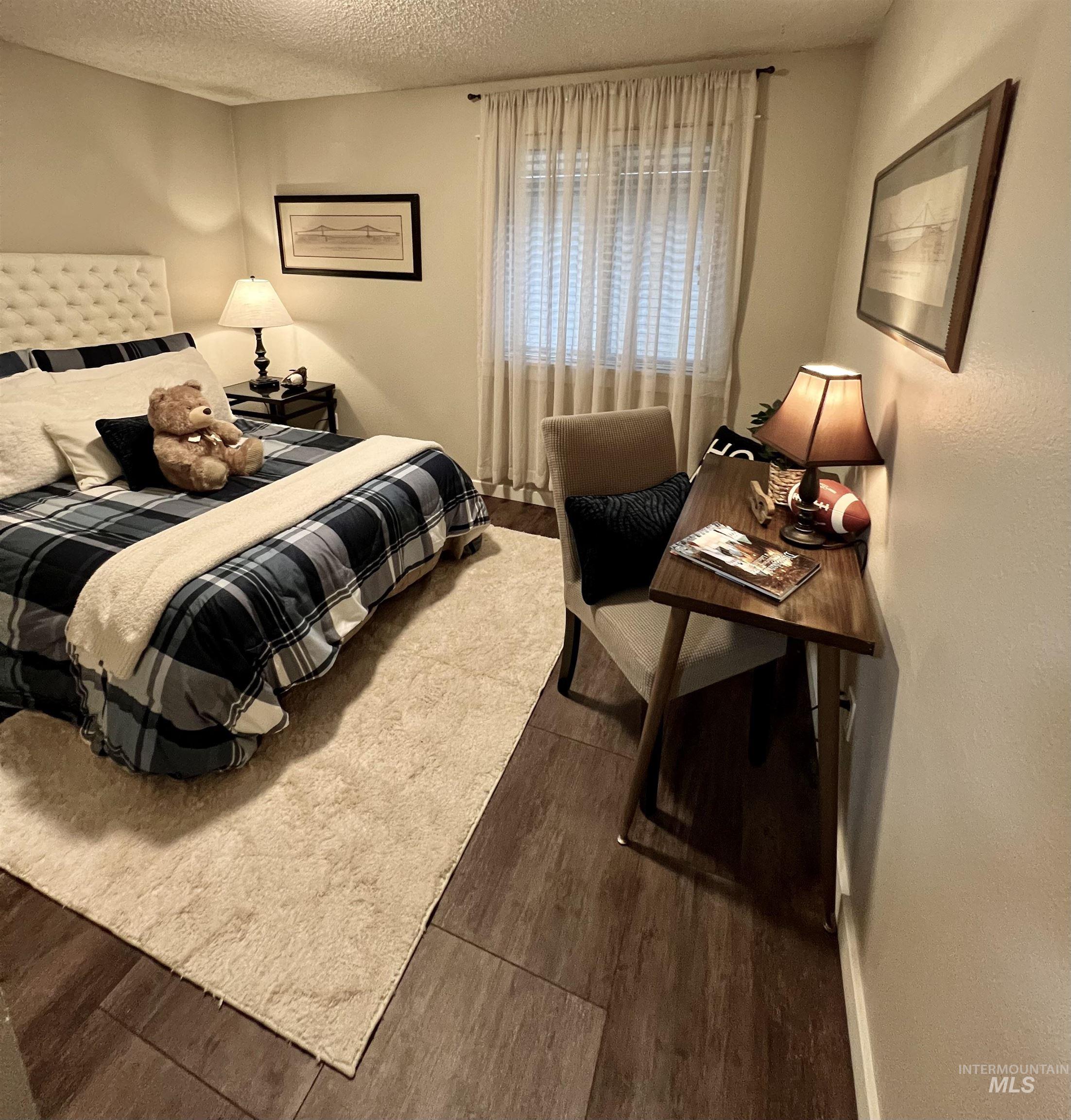 Bedroom with a textured ceiling and dark wood-style floors