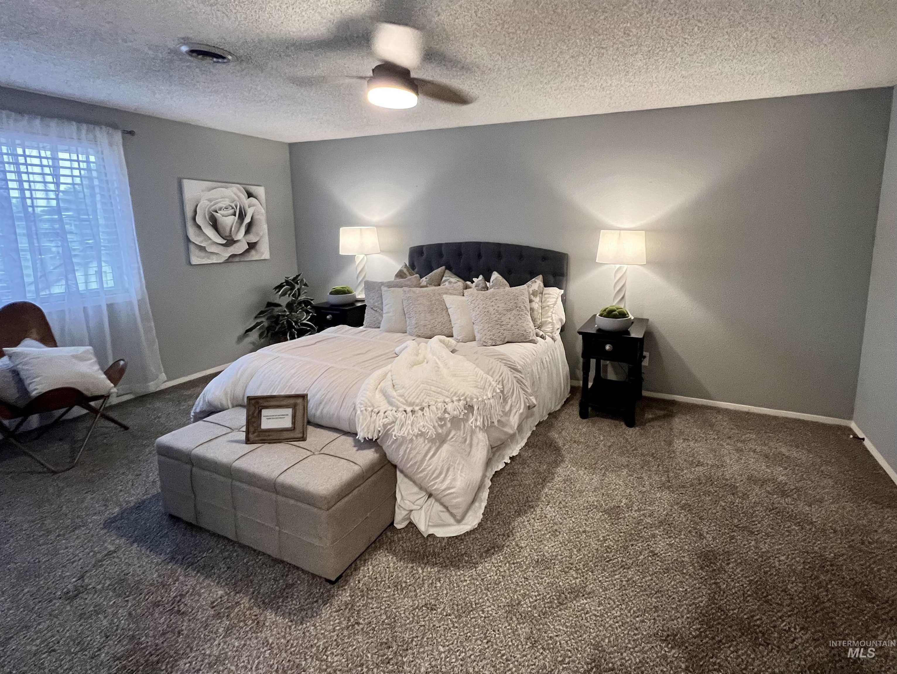 Carpeted bedroom with a textured ceiling and ceiling fan
