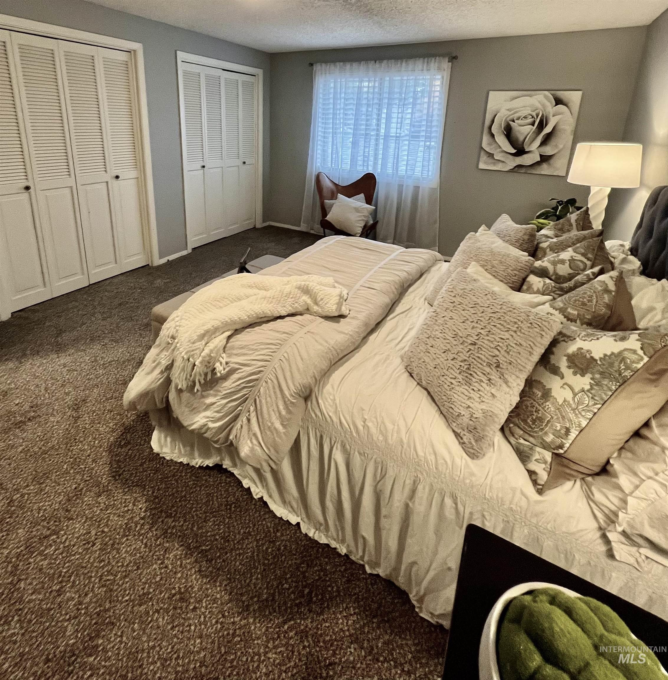 Carpeted bedroom featuring two closets and a textured ceiling