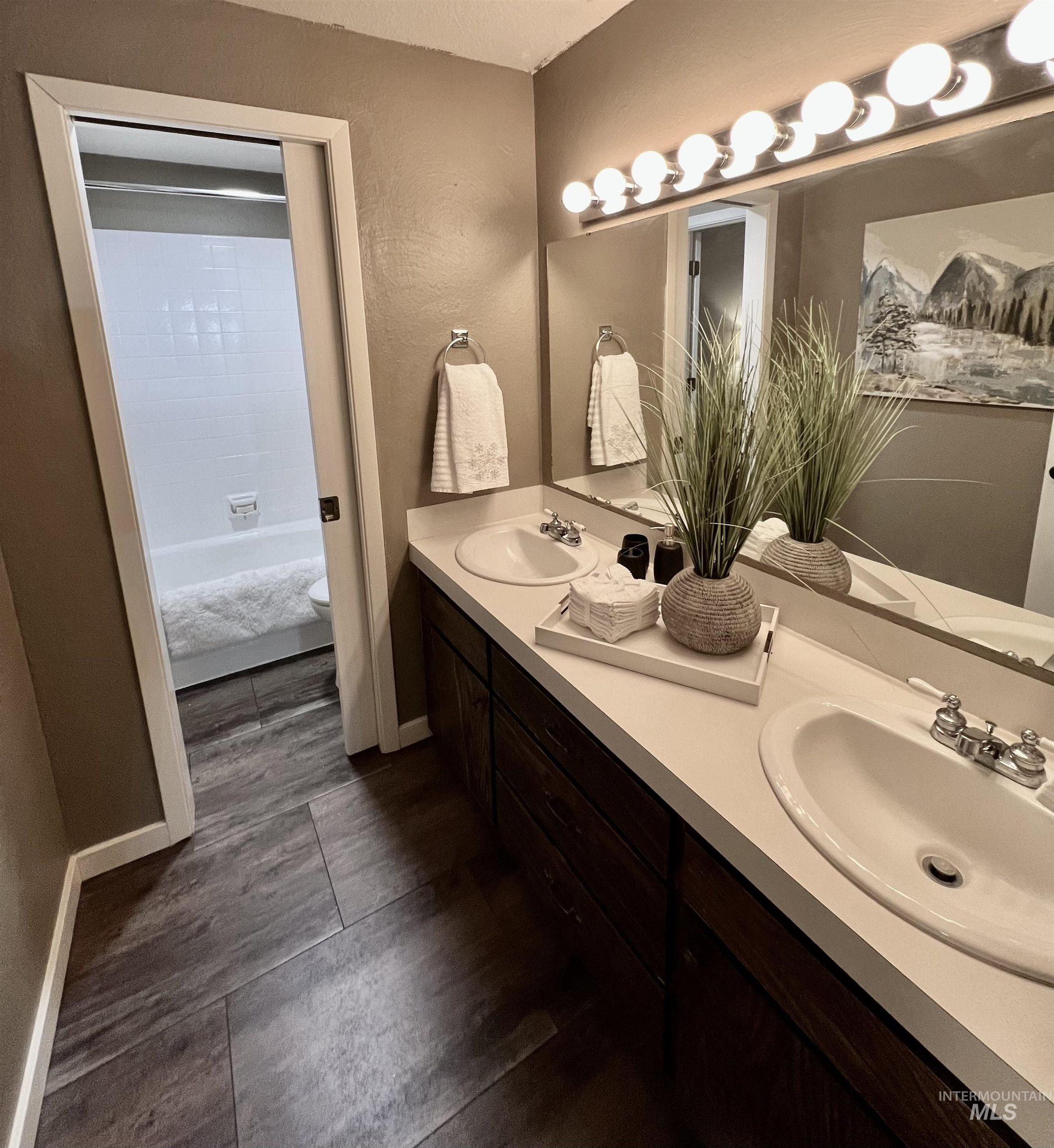 Full bath featuring double vanity and a textured wall