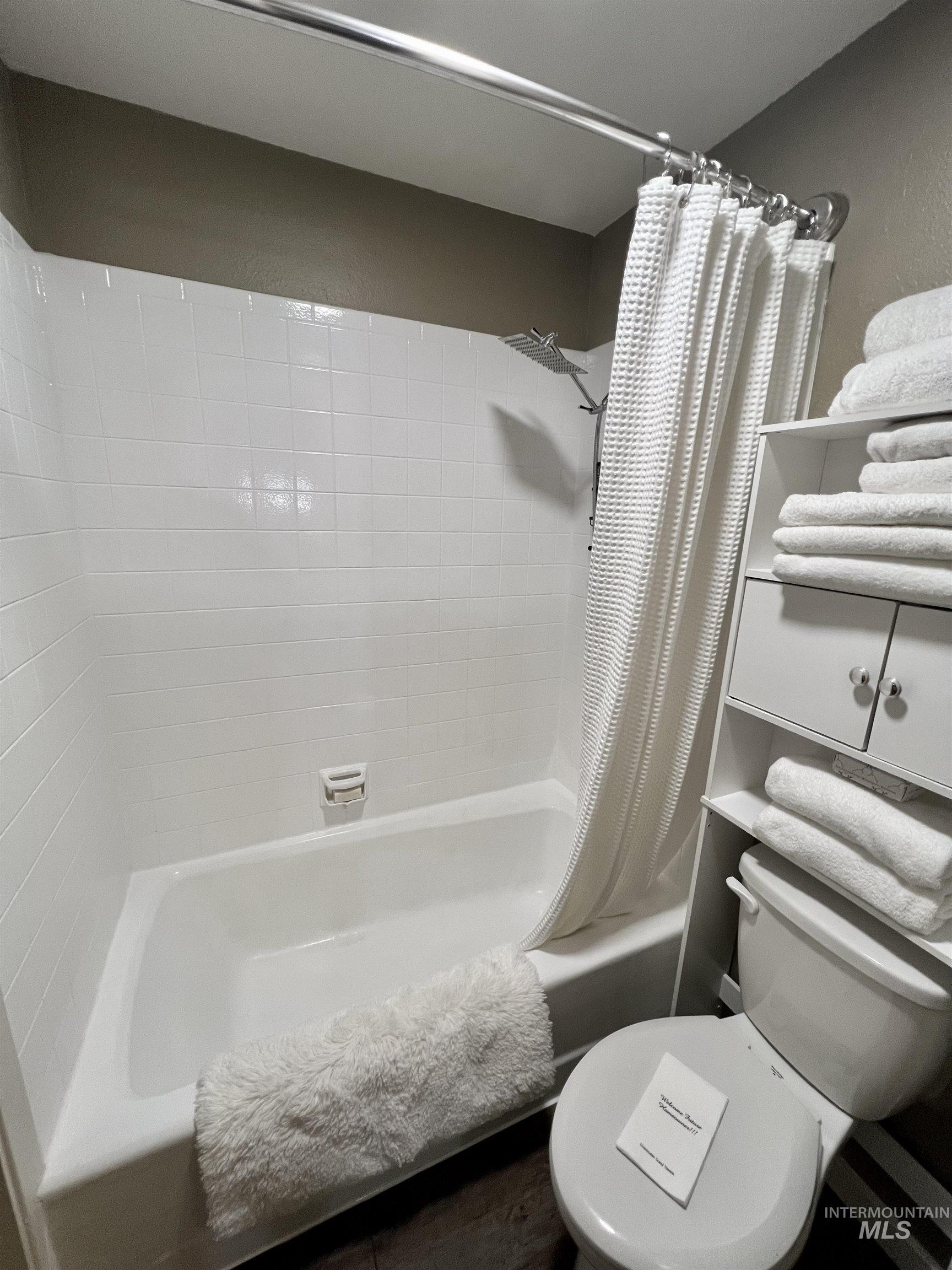 Bathroom with shower / bath combination with curtain and toilet