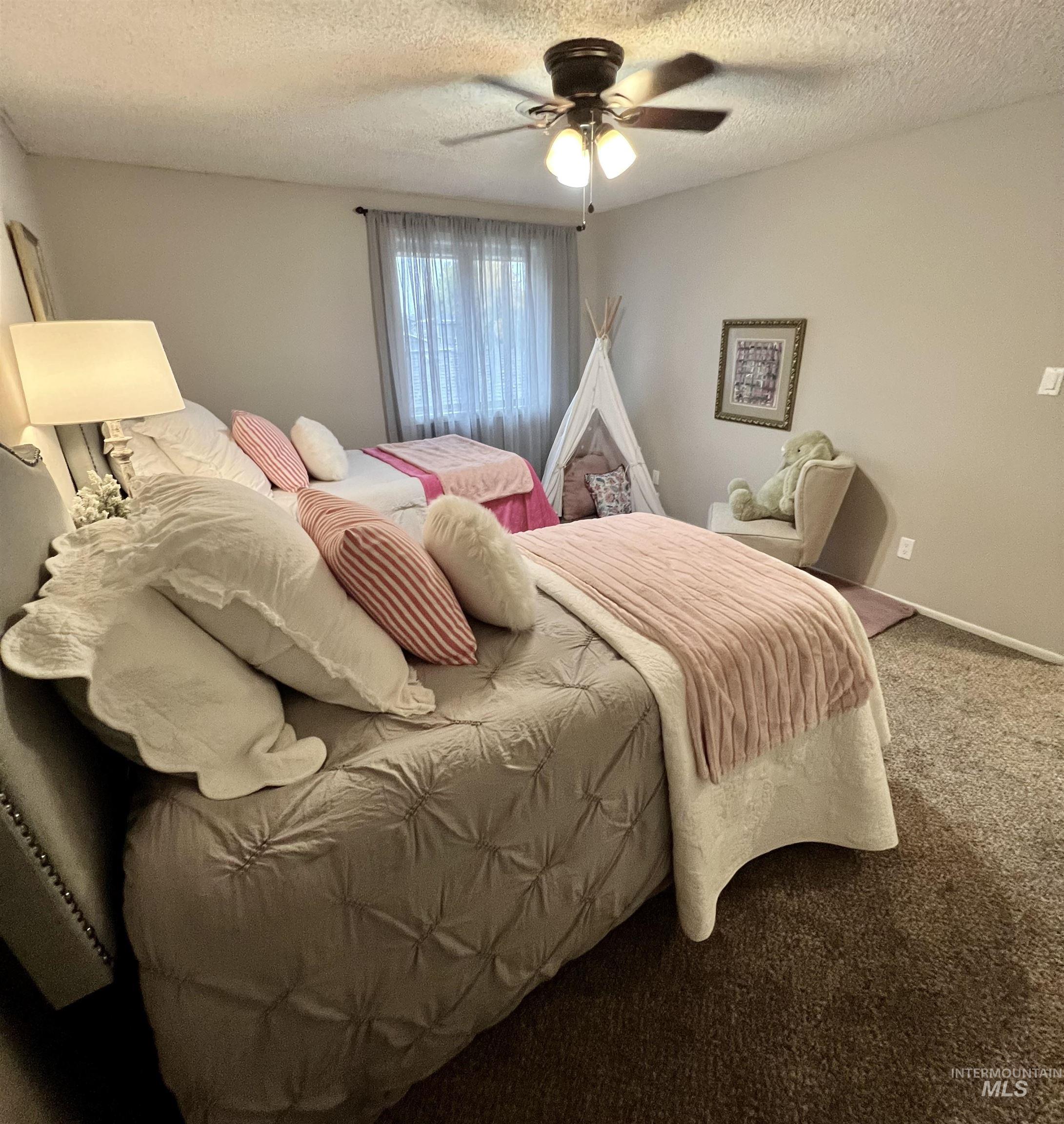Bedroom with a textured ceiling, carpet, and a ceiling fan