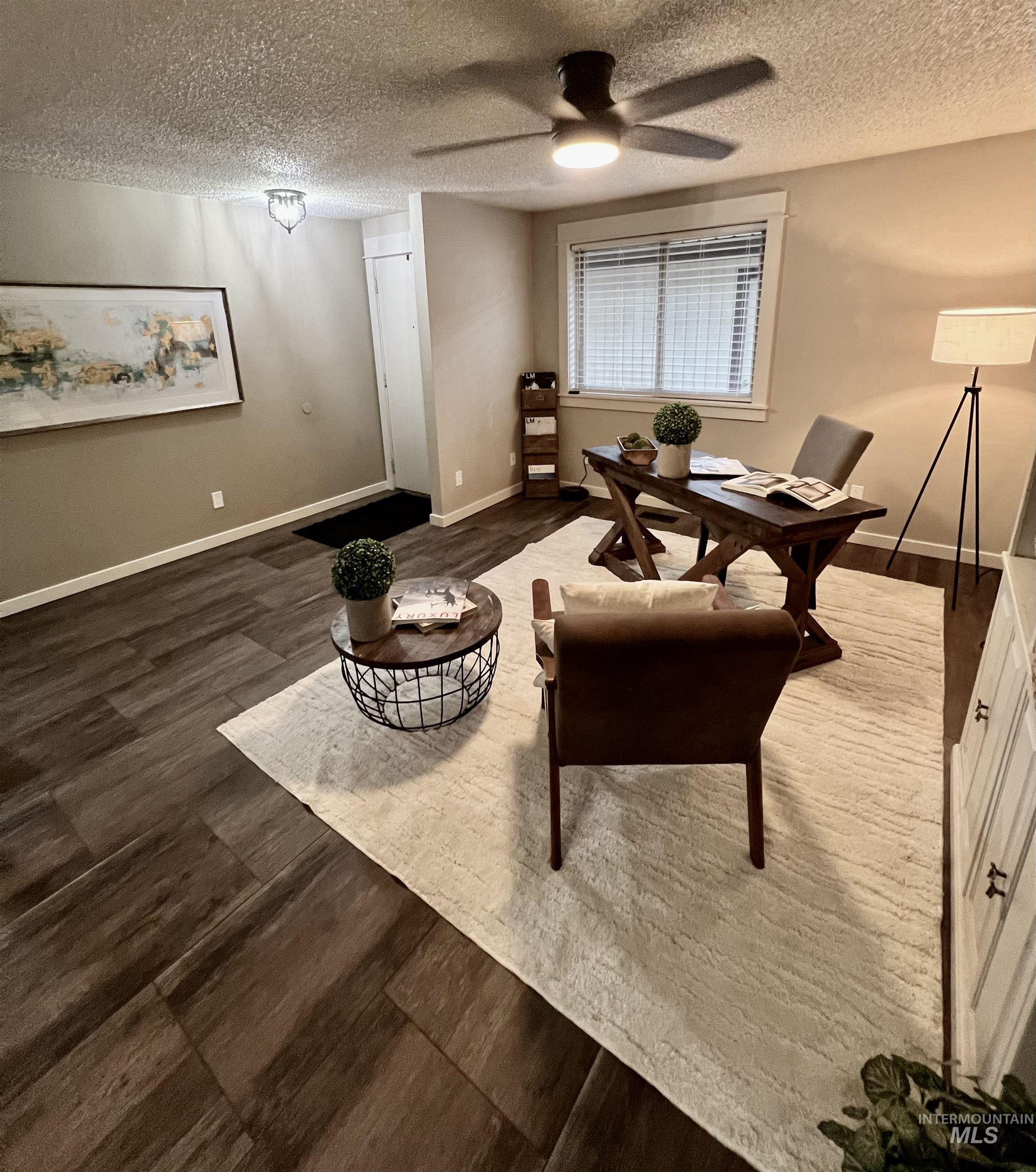 Living area with a textured ceiling, wood finished floors, and a ceiling fan