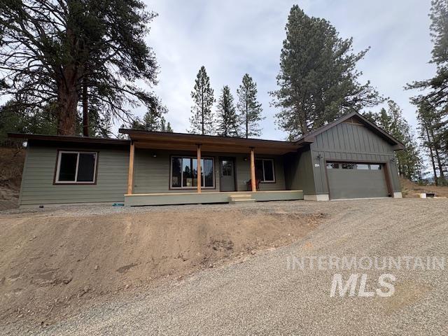 Single story home with a garage, driveway, board and batten siding, and covered porch