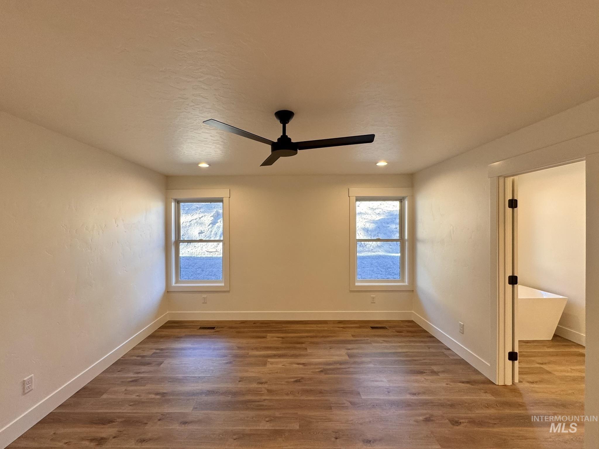 Unfurnished bedroom with multiple windows, wood finished floors, a ceiling fan, a textured ceiling, and recessed lighting