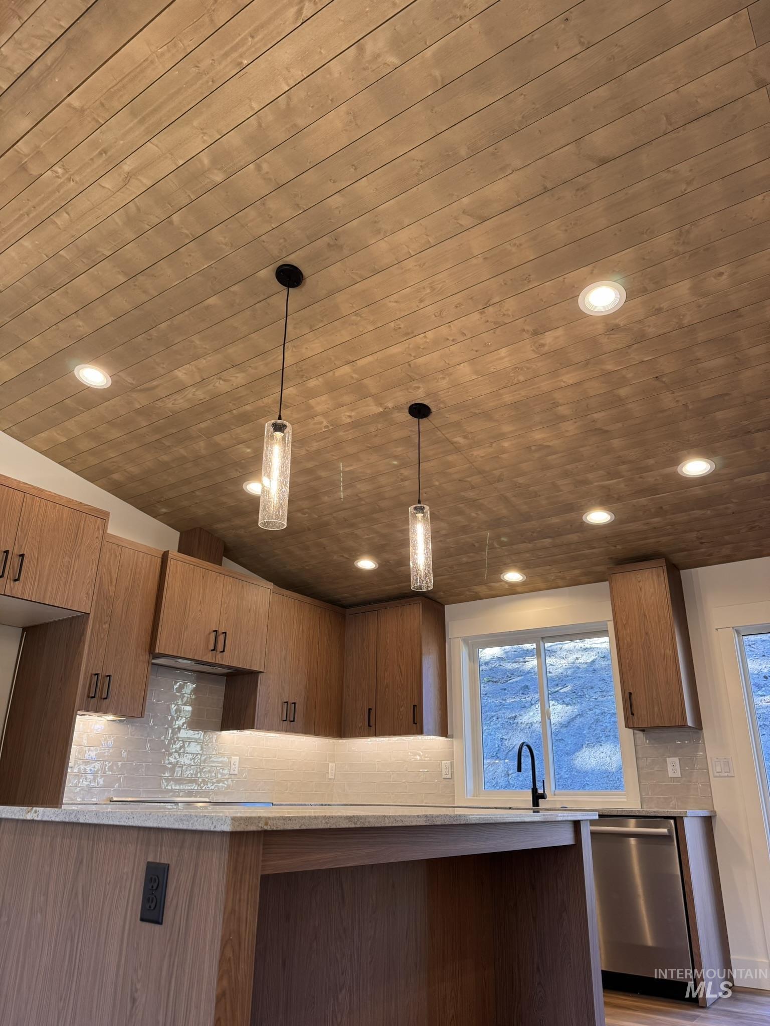 Kitchen featuring tasteful backsplash, hanging light fixtures, light stone counters, modern cabinets, and recessed lighting