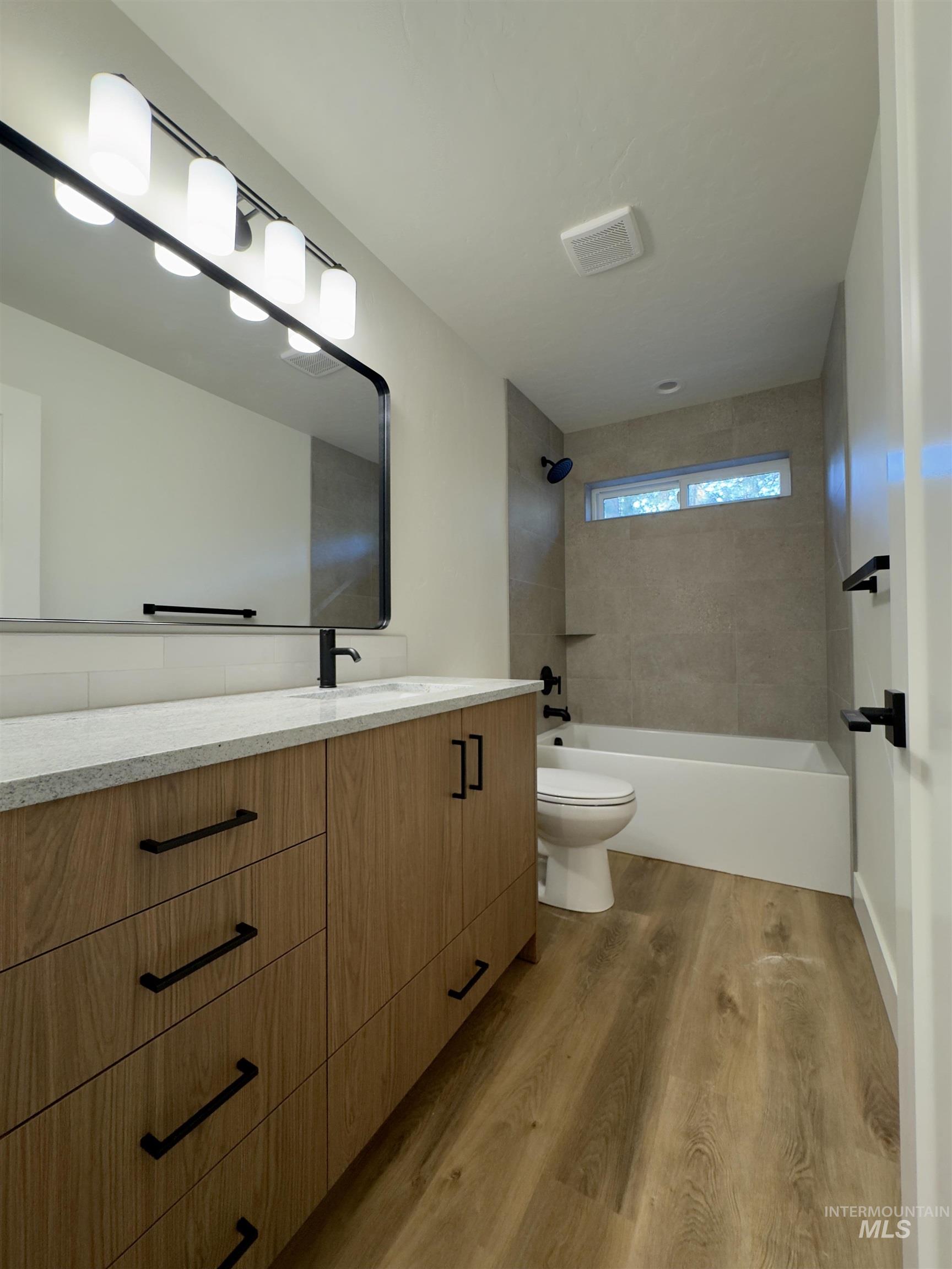 Full bath with vanity, shower / tub combination, and light wood finished floors
