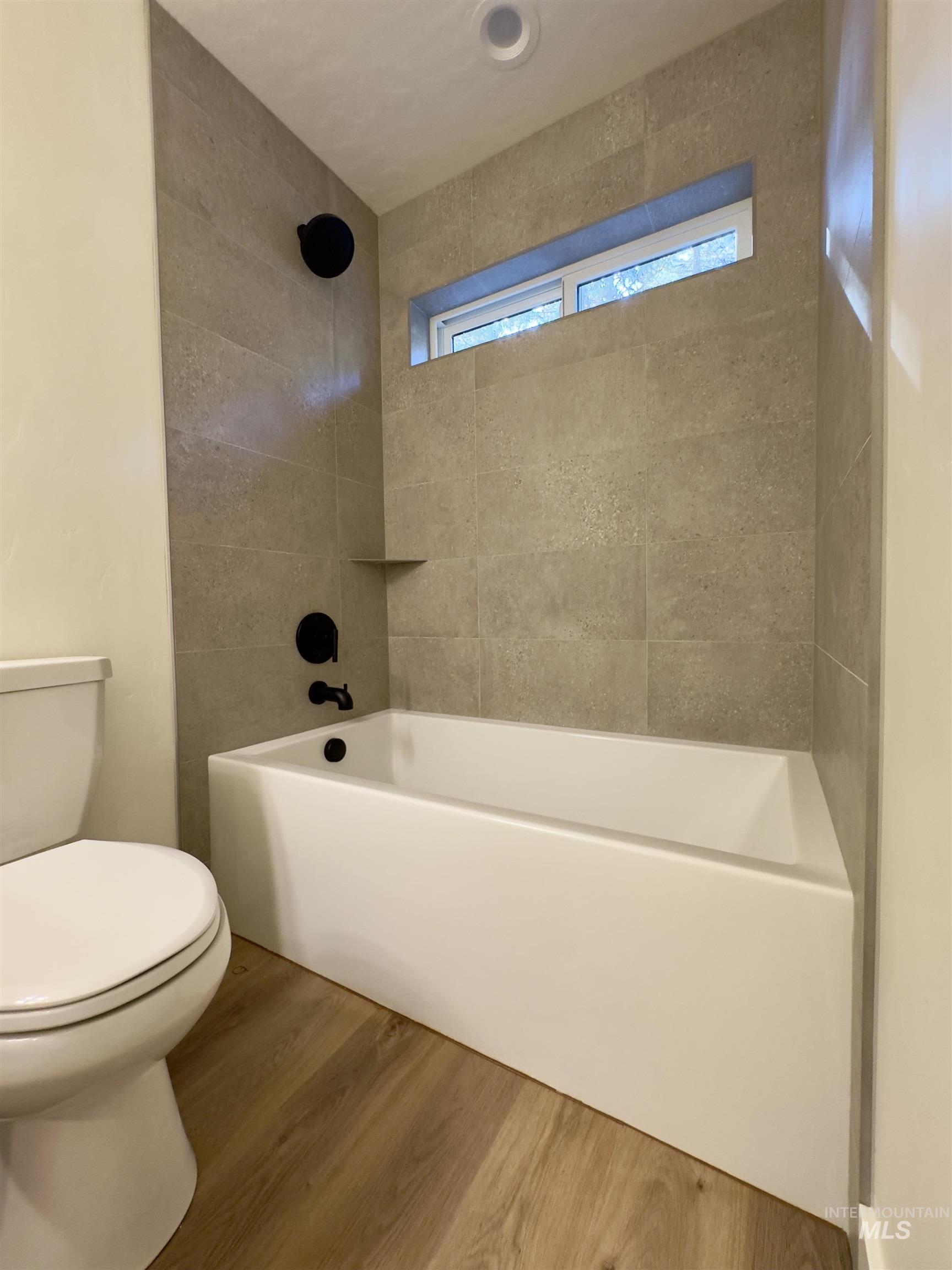 Full bath featuring wood finished floors and bathtub / shower combination