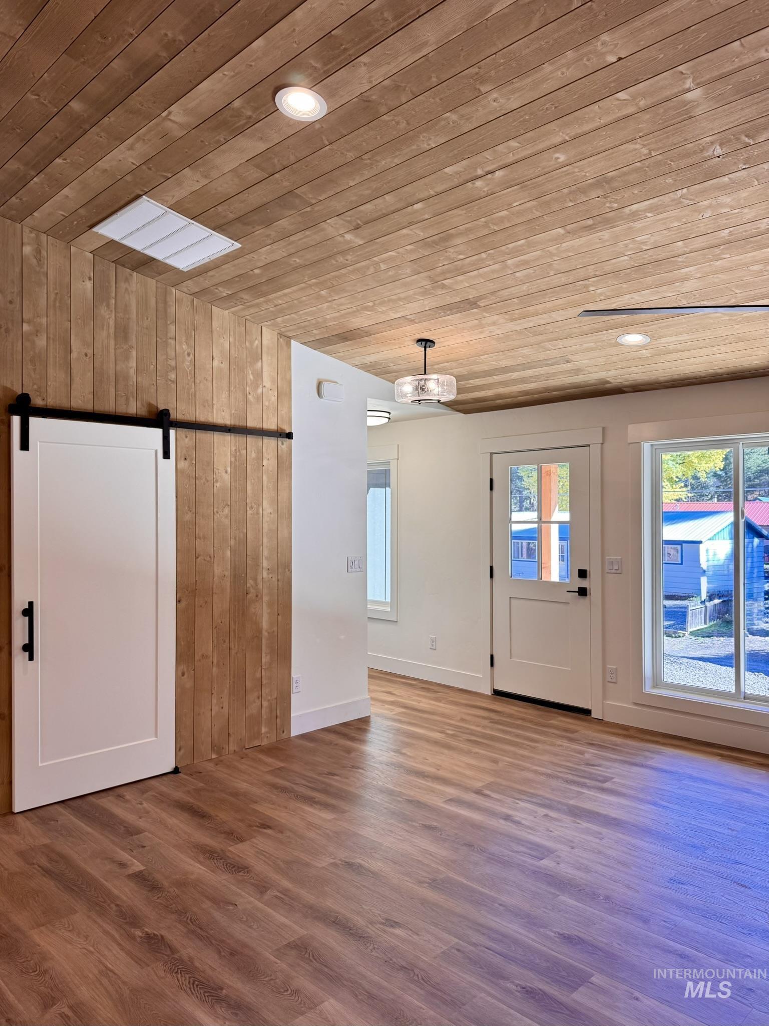 Foyer entrance featuring a barn door, wooden ceiling, wooden walls, wood finished floors, and recessed lighting